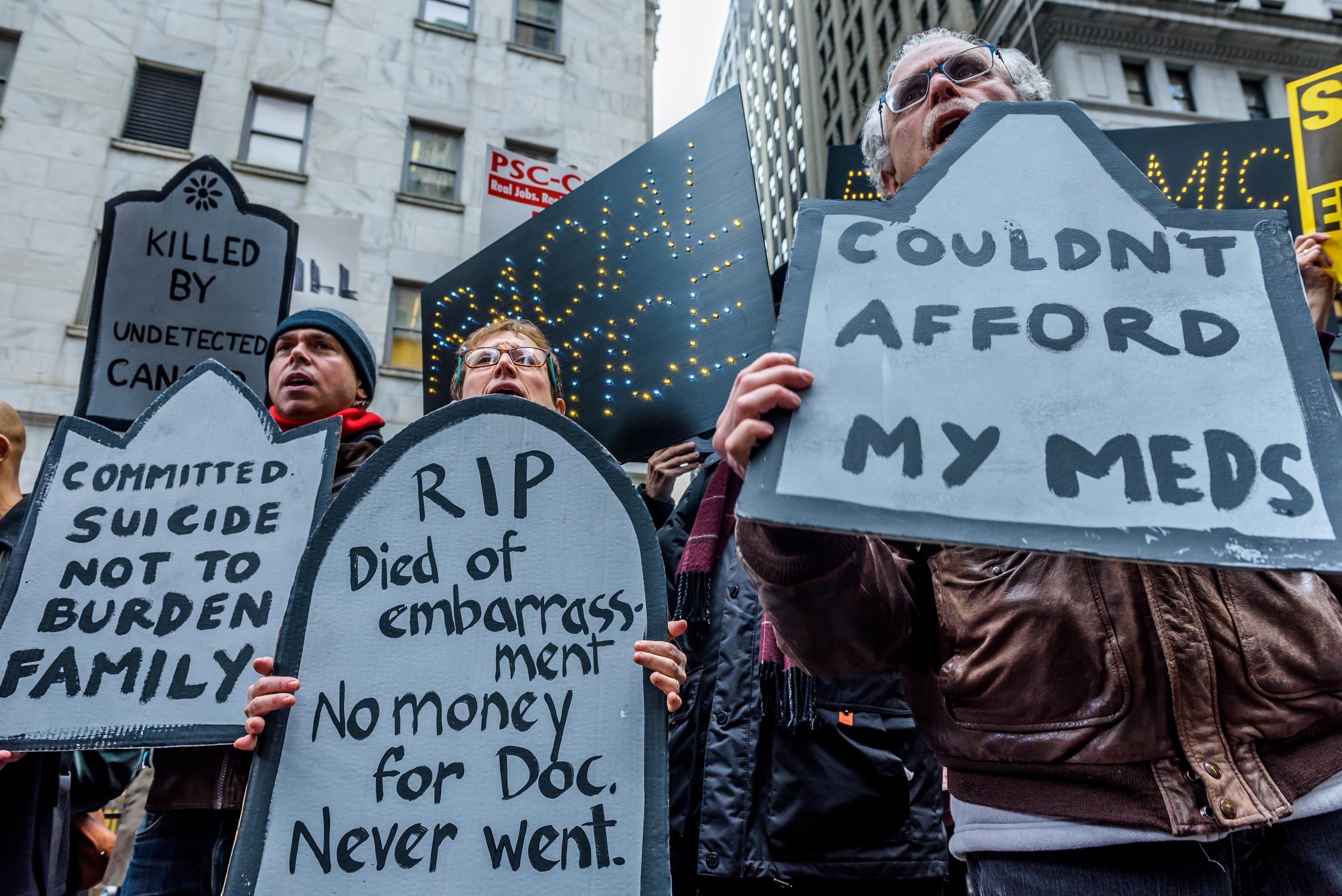 Protesters hold signs denouncing the Republican Party's Tax Cuts and Jobs Act outside the New York Stock Exchange on December 19, 2017. 