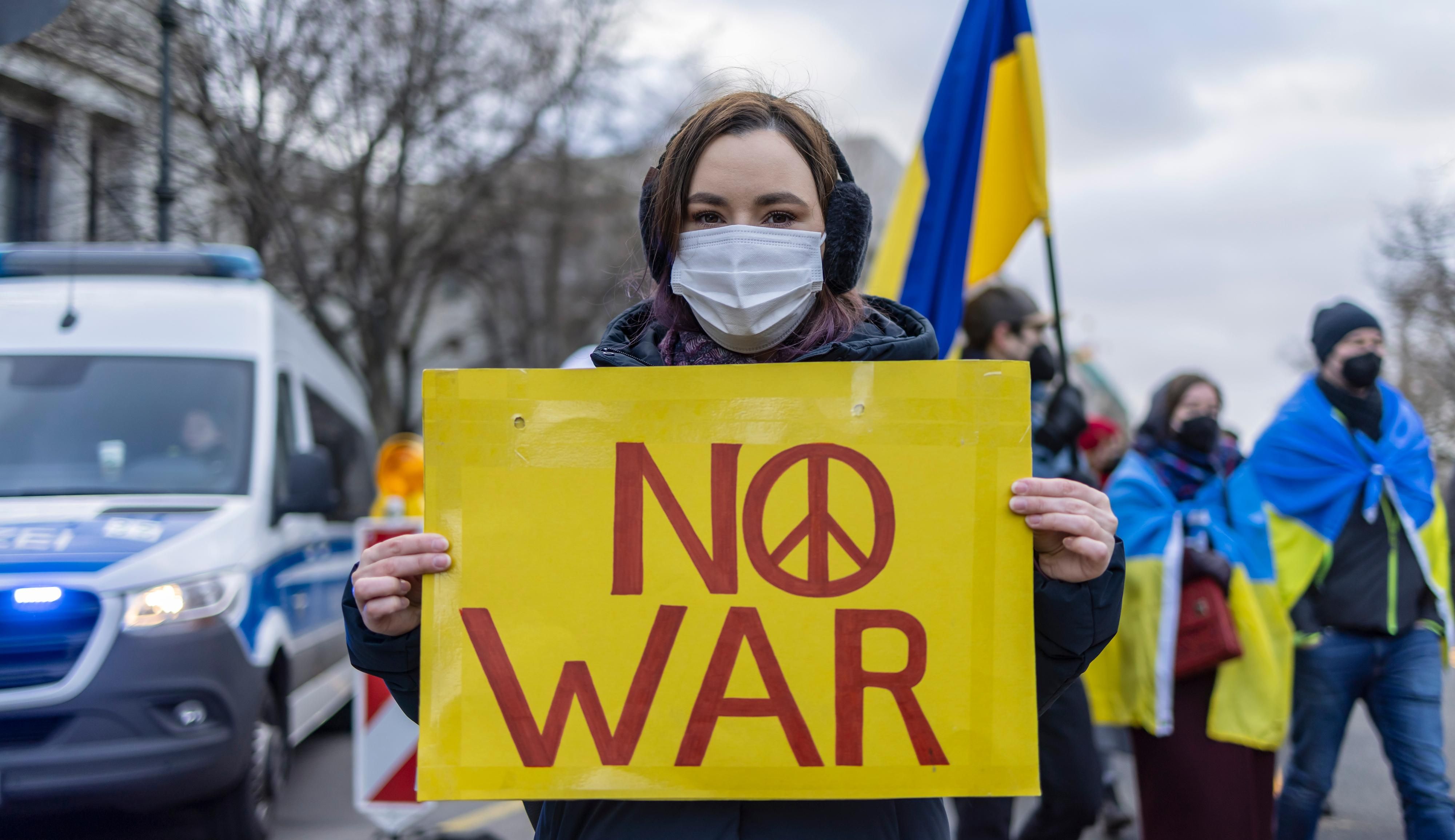 Protester with a sign that says "No War" outside the Russian embassy in Berlin, Germany