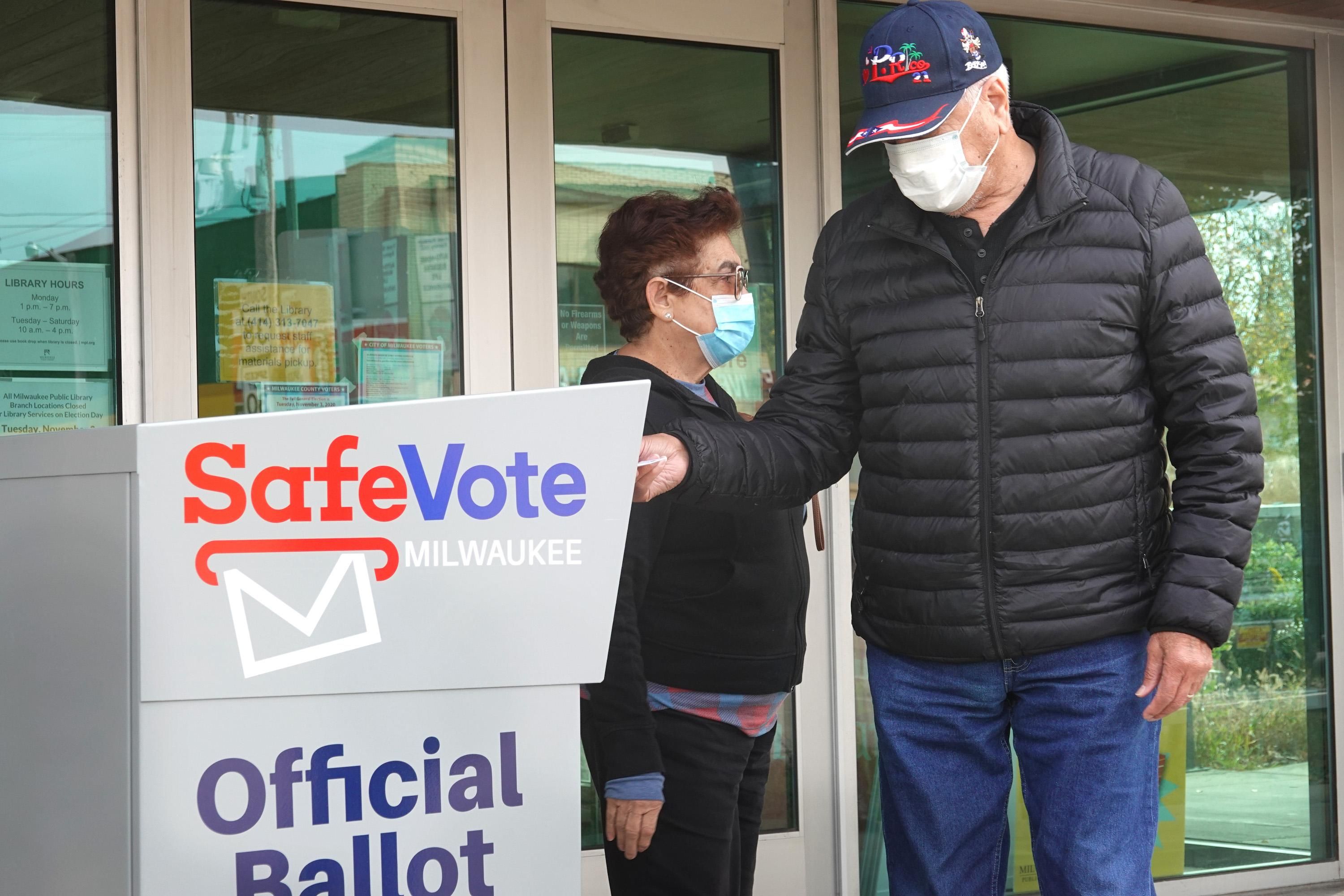 Residents drop mail-in ballots in an official ballot box outside of the Tippecanoe branch library on October 20, 2020 in Milwaukee