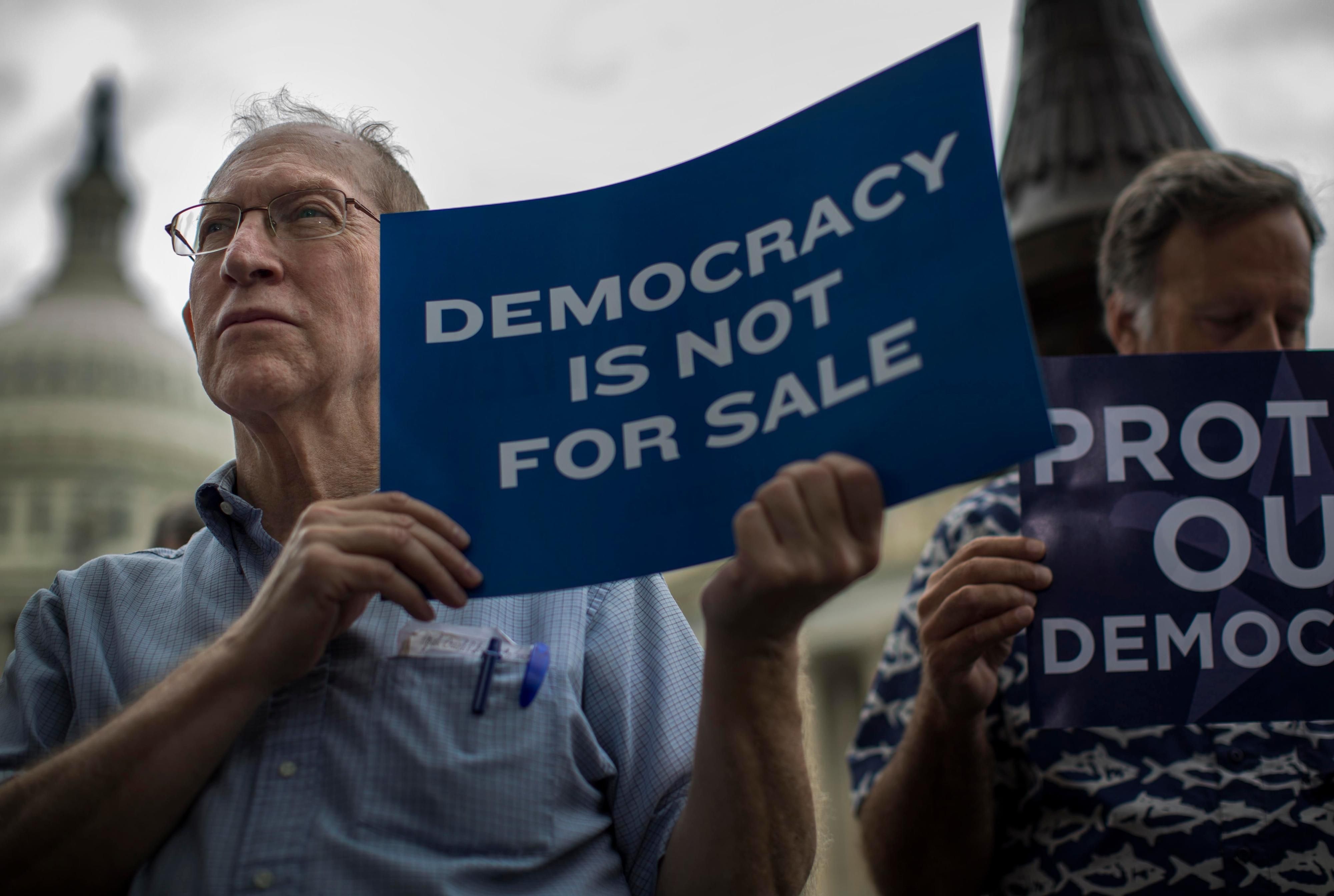 Man holding sign that says "Democracy Is Not for Sale"