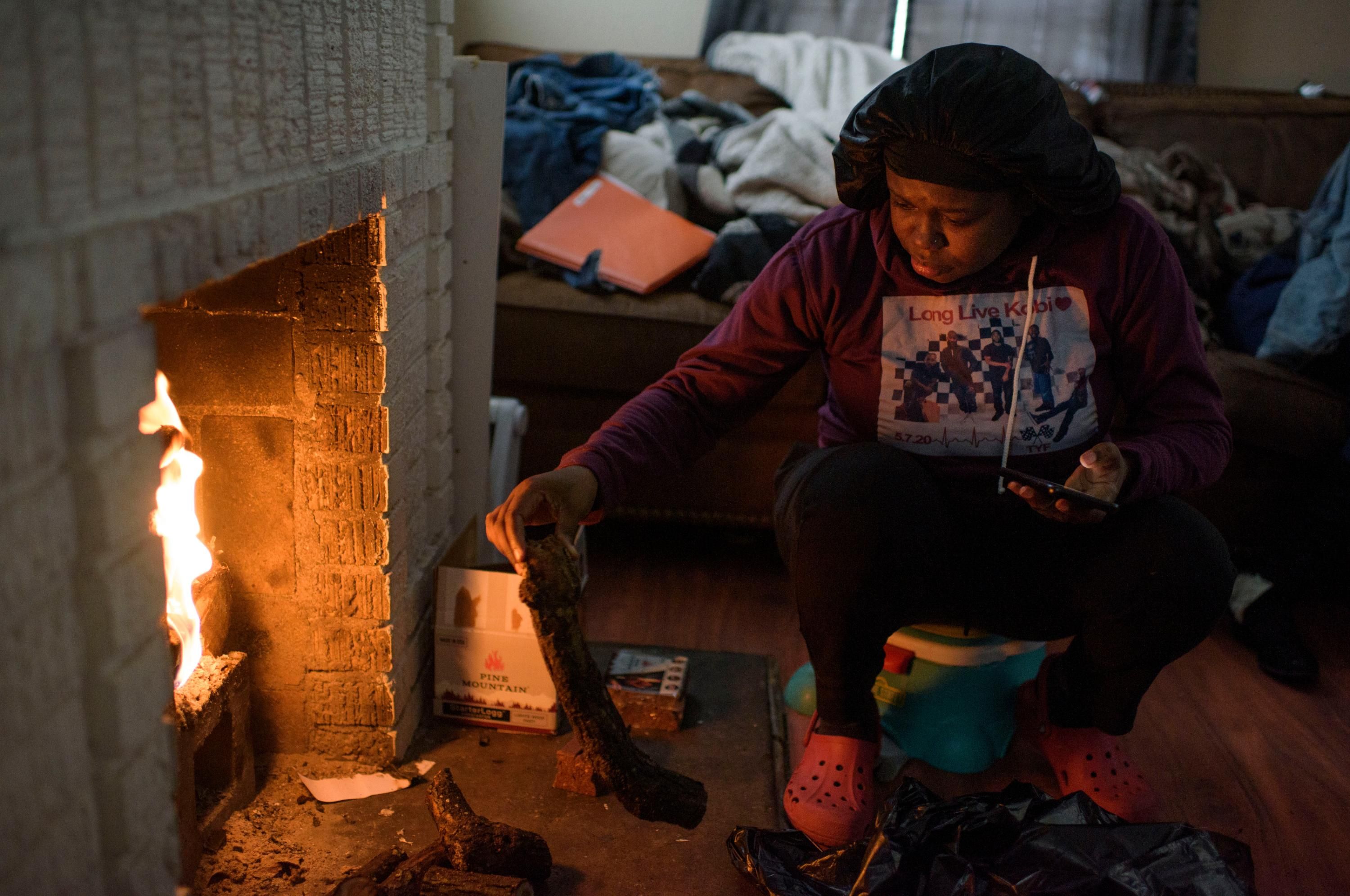 A woman uses a fire to provide heat in her home