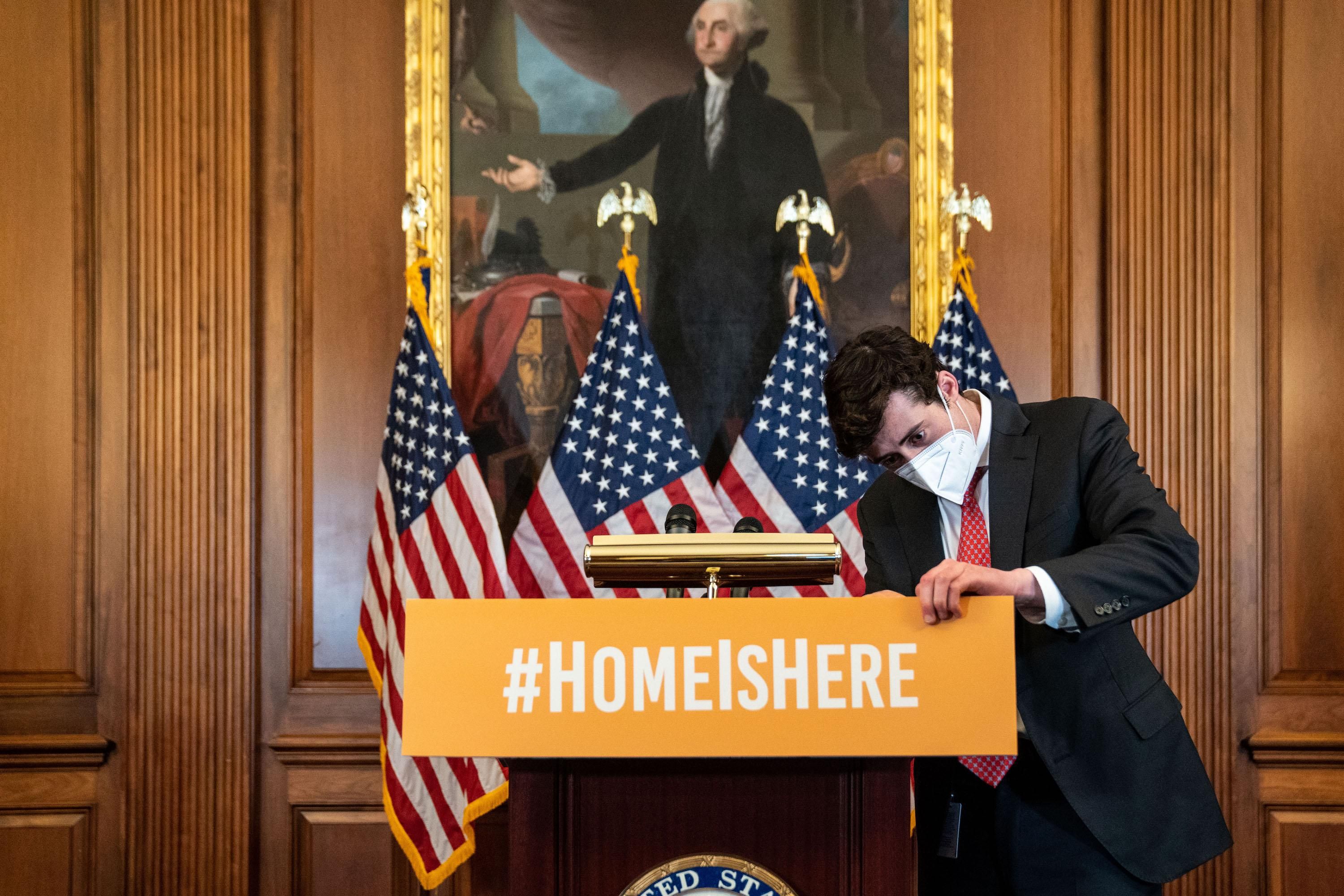 A congressional staffer adjusts a sign before the start of a press conference