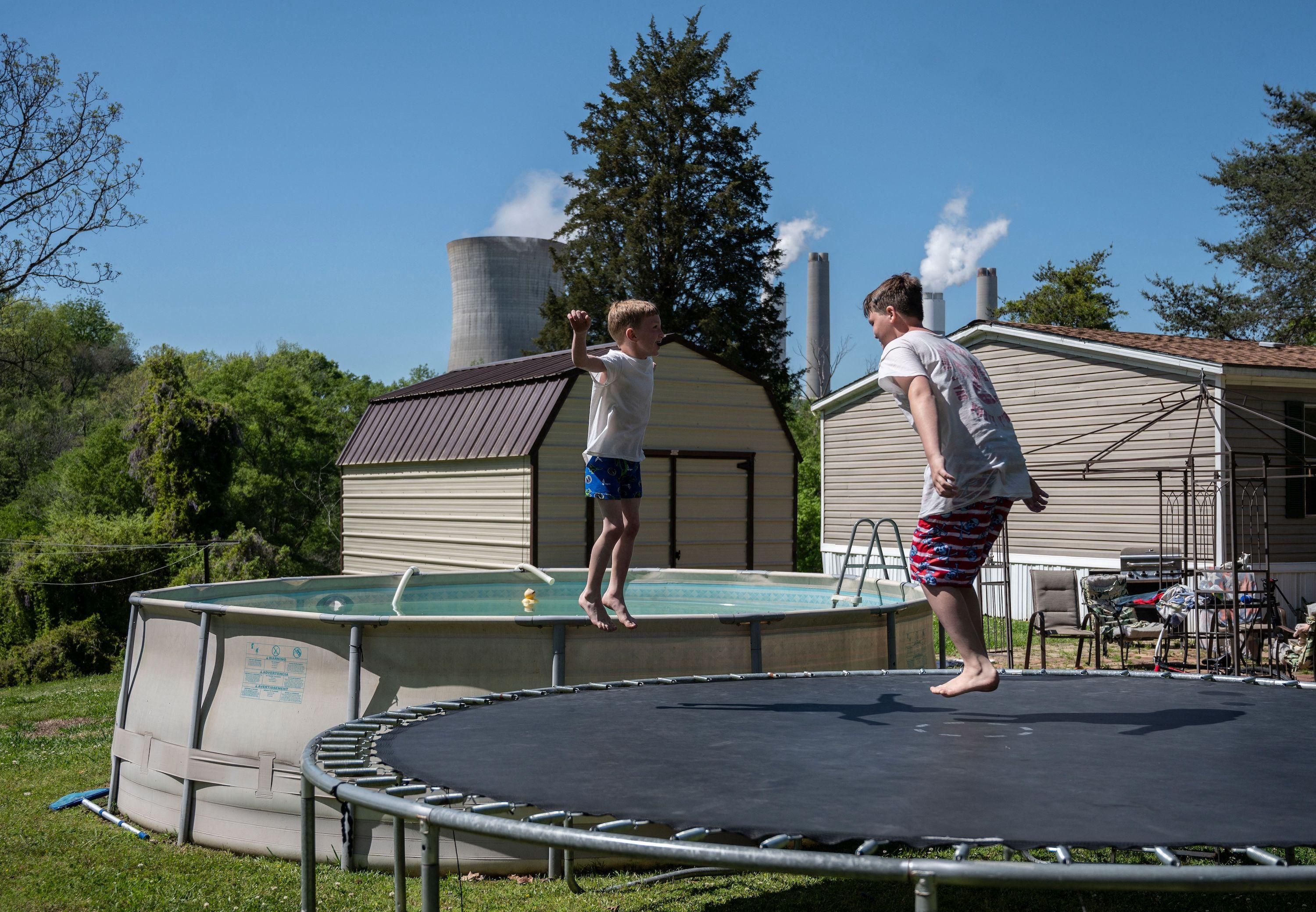 Kids jump on a trampoline at their grandparents' home as steam rises from the Miller coal power plant in Adamsville, Alabama on April 11, 2021. (Photo: by Andrew Caballero-Reynolds/AFP via Getty Images)