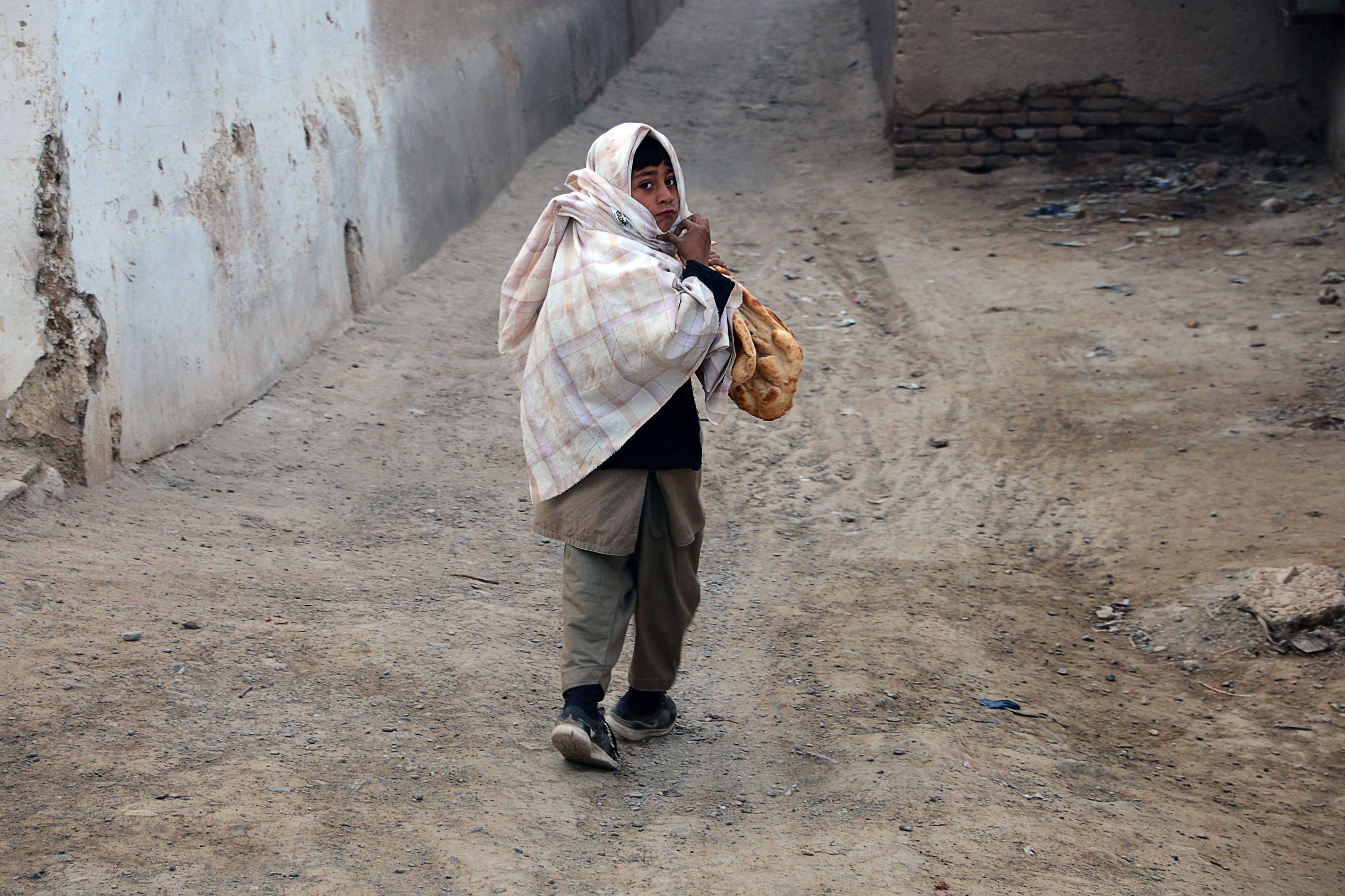 A child holding bread walks early in the morning in Kandahar, Afghanistan on February 5, 2022.