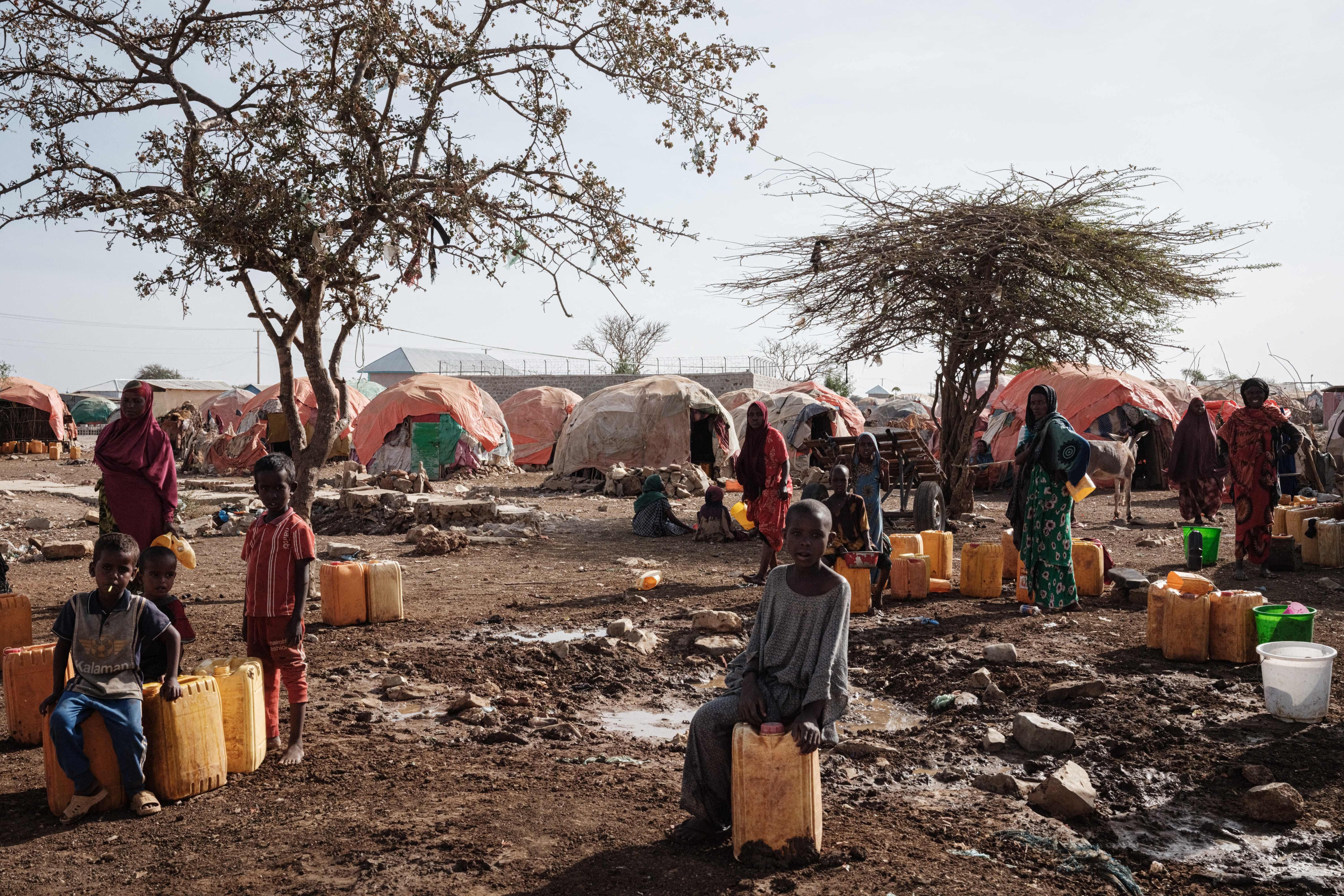 People wait for water with containers at a camp for internally displaced persons in Baidoa, Somalia, on February 13, 2022.