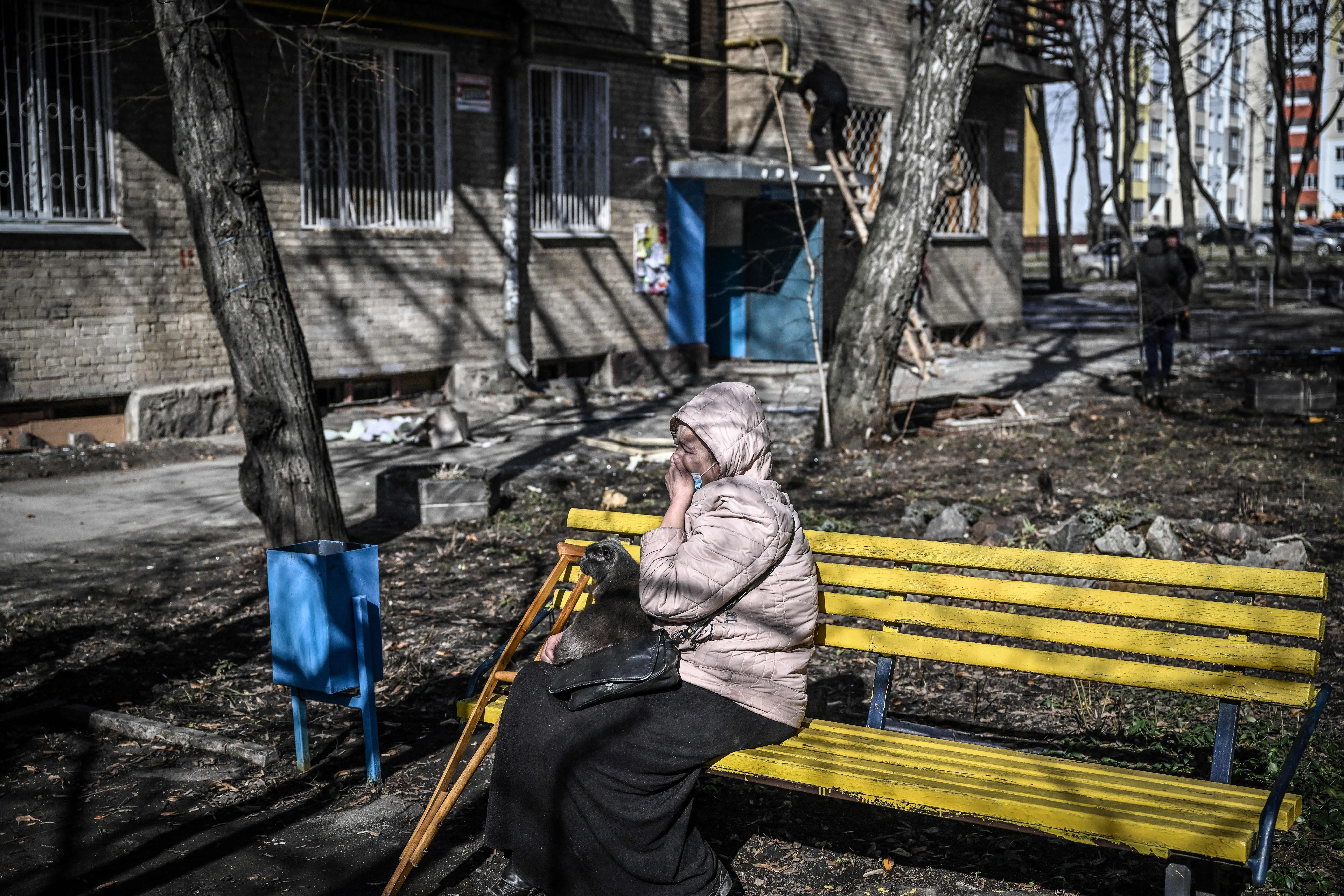 A woman weeps as she sits outside a building that was damaged by bombing in the eastern Ukraine town of Kharkiv on February 24, 2022. 