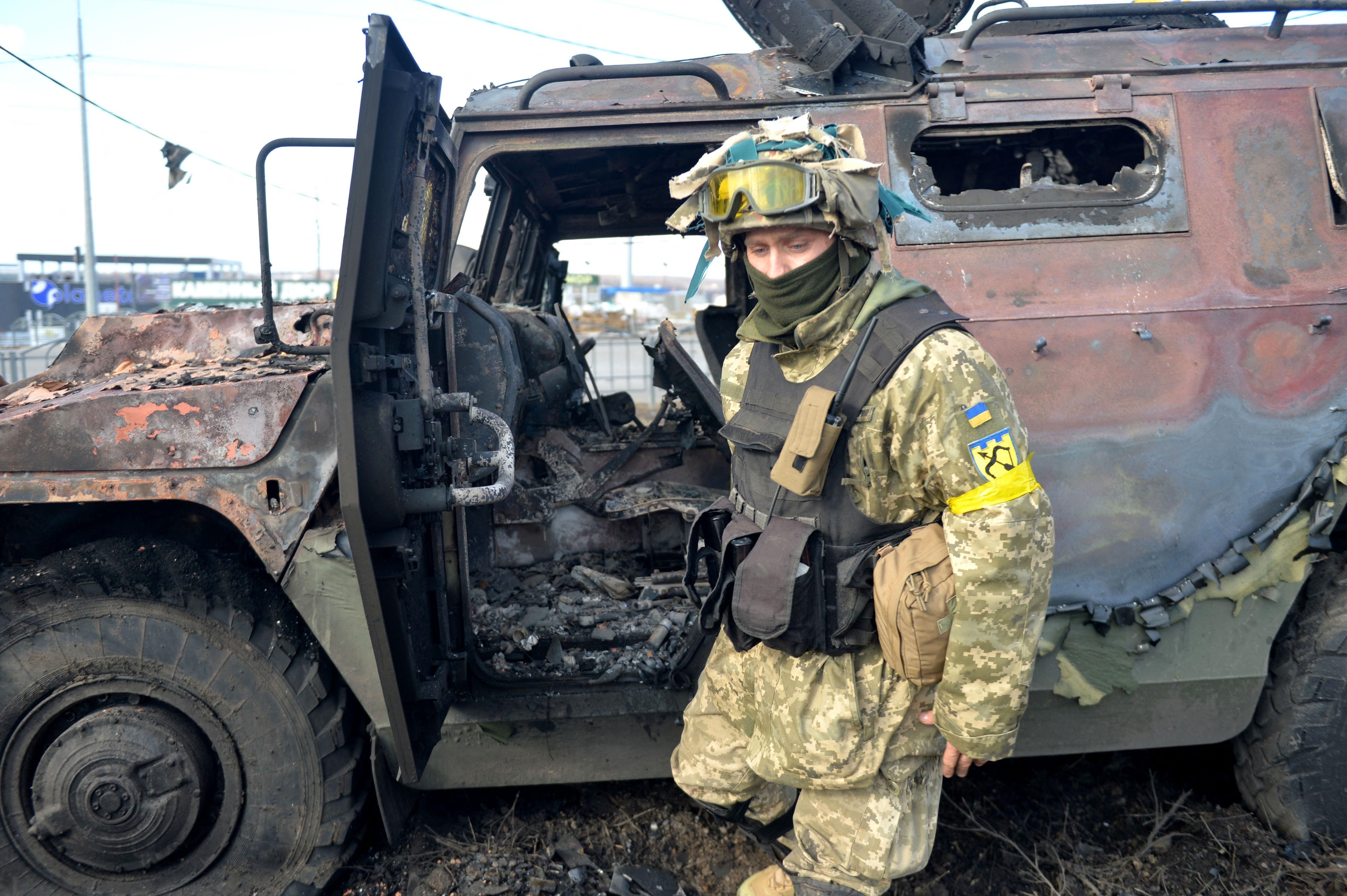 Ukraine soldier examines destroyed Russian military vehicle