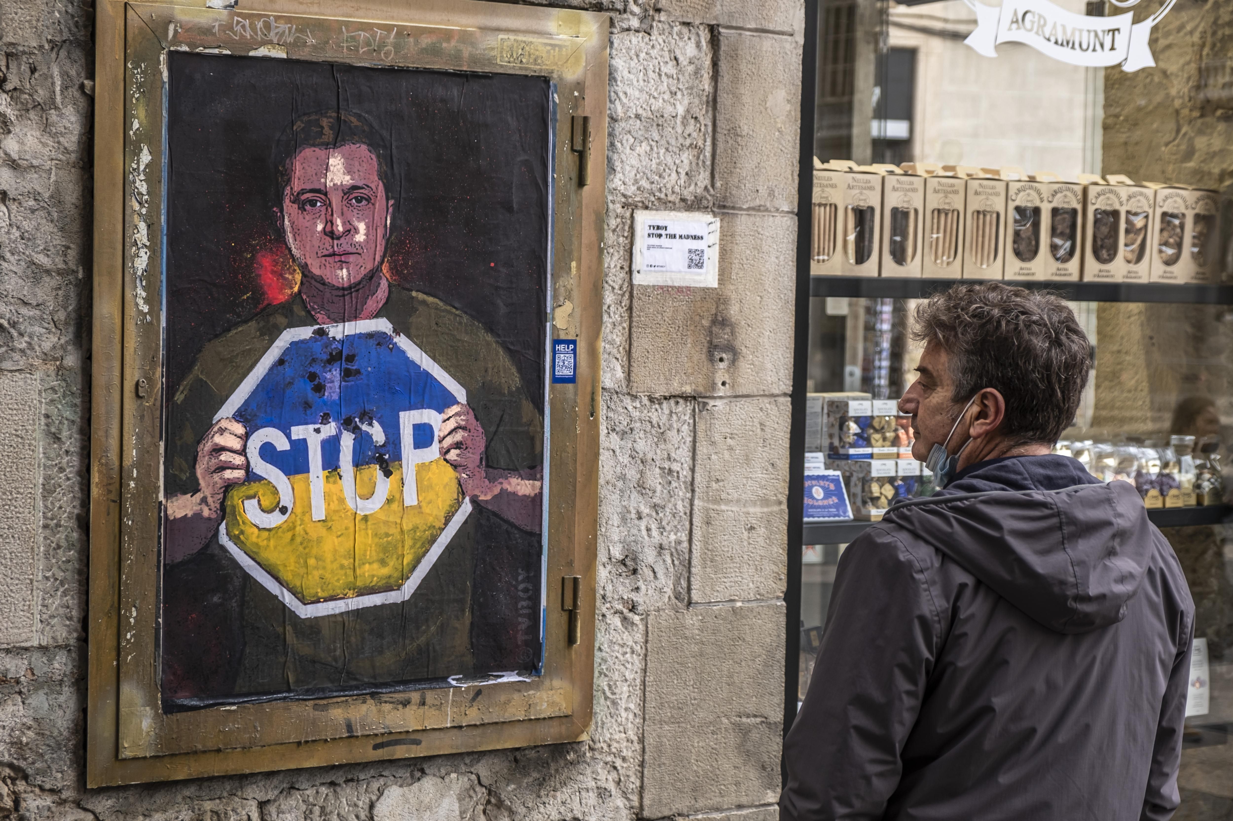 A person in Barcelona, Spain is seen observing the graphic representation of Ukrainian President Volodymyr Zelenskyy calling for an end to Russia's invasion on March 7, 2022. 