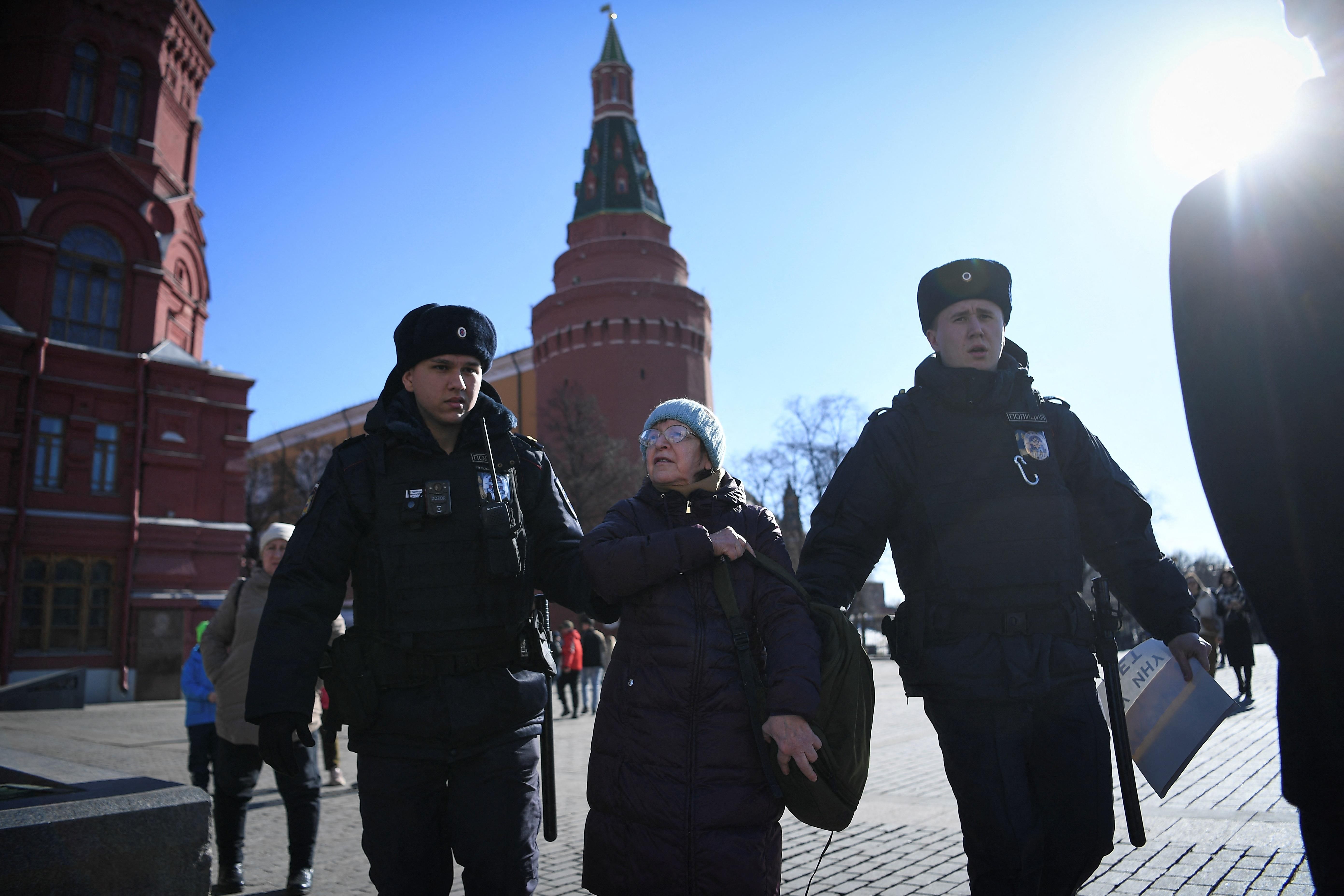Police officers detain an elderly woman as she protests against Russia's invasion of Ukraine, in central Moscow on March 20, 2022.