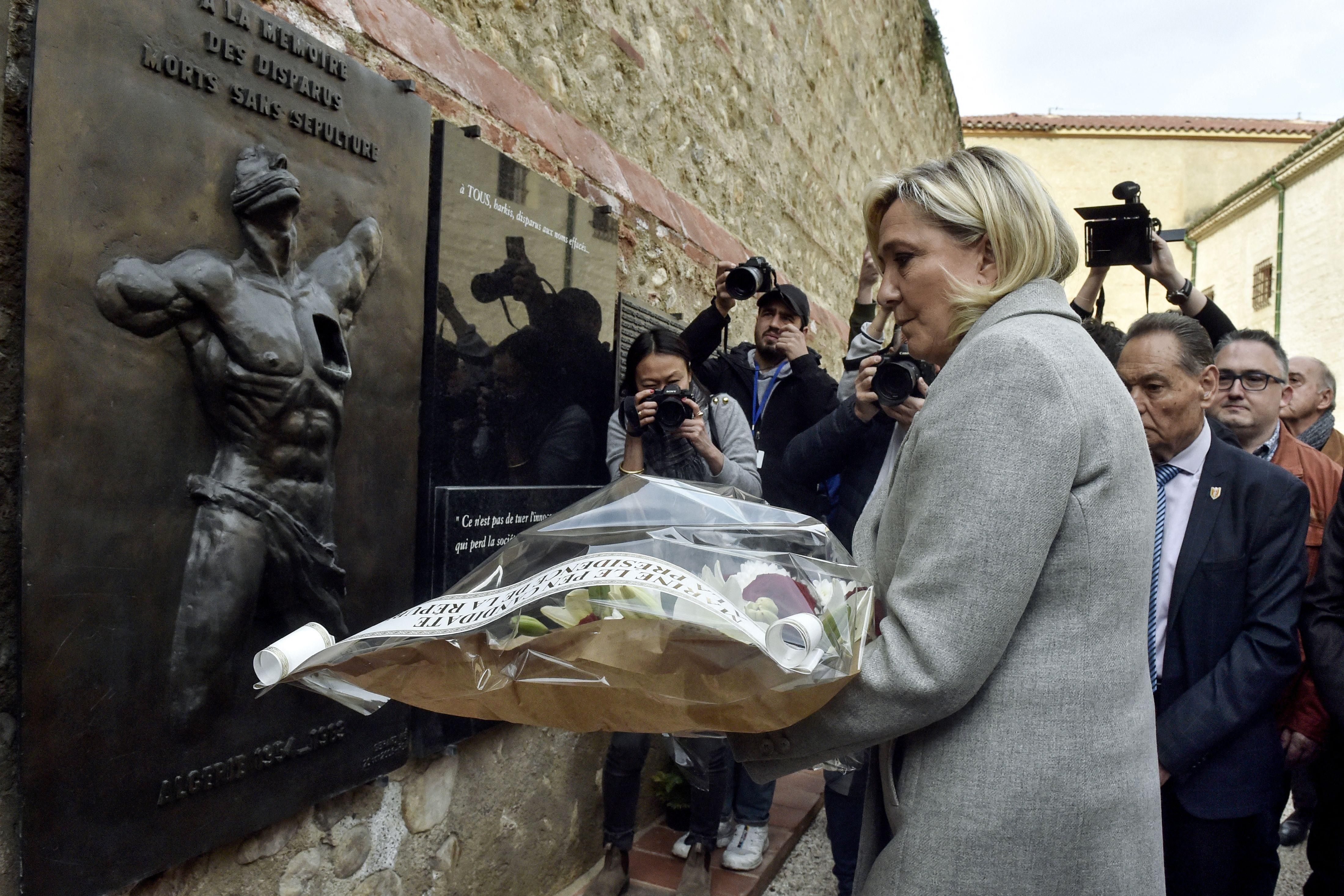 French far-right presidential candidate Marine Le Pen lays flowers at the Wall of the Disappeared, a memorial to colonists in Algeria, during a campaign stop in Perpignan, southern France, on April 8, 2022. 