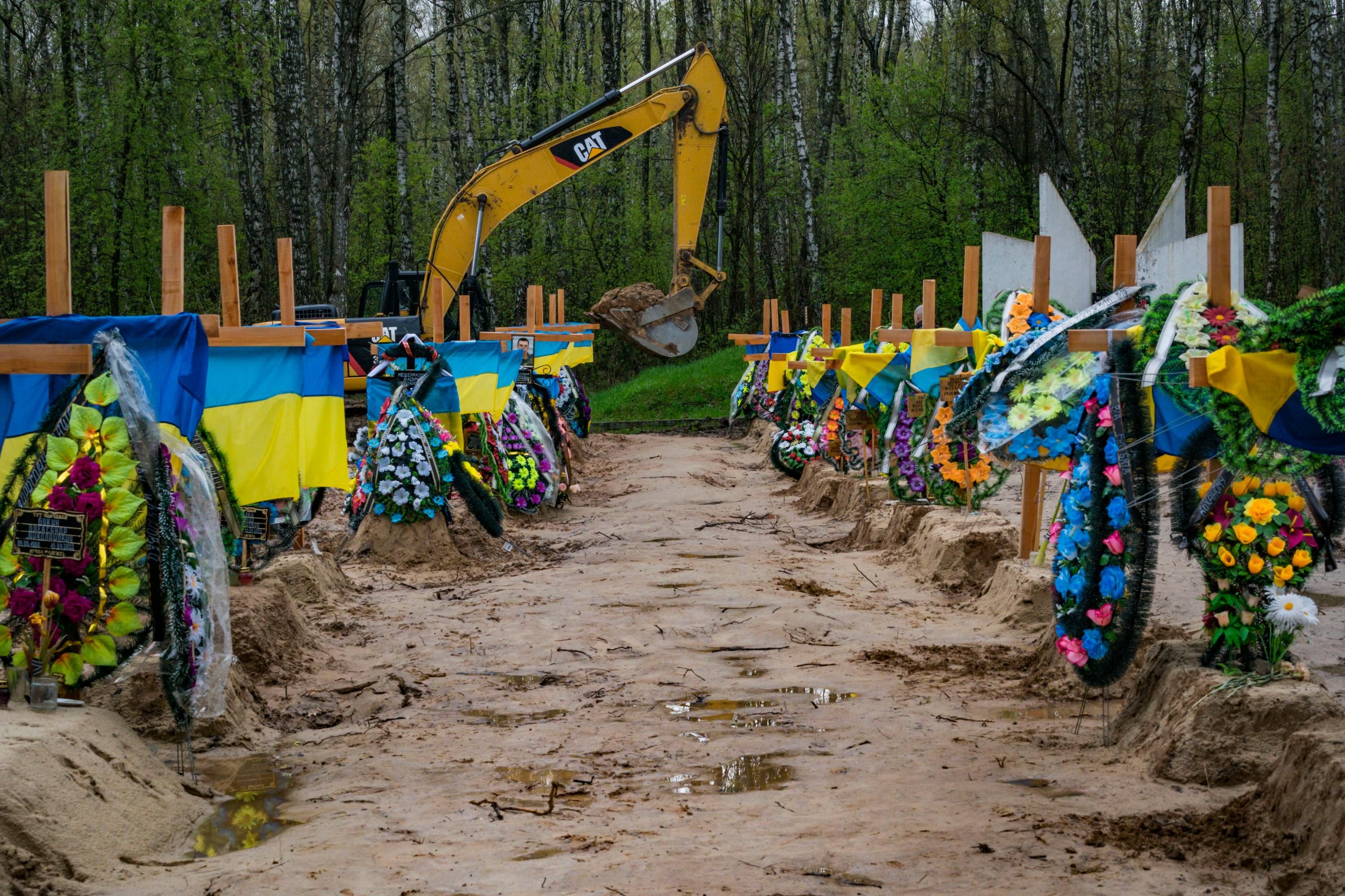 A bulldozer digs graves in Ukraine