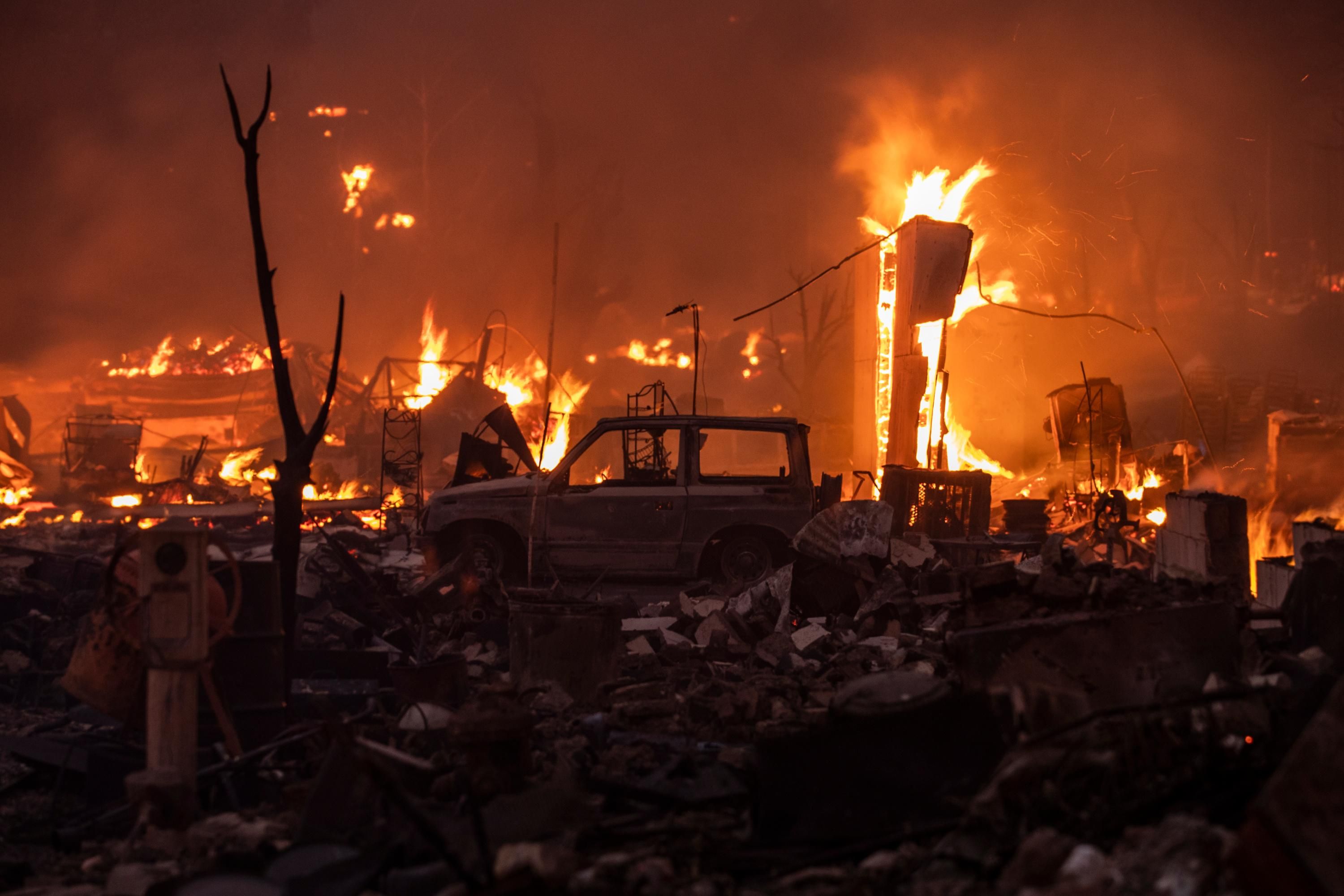 A damaged vehicle stands amongst burning structures during the Dixie Fire in Greenville, California