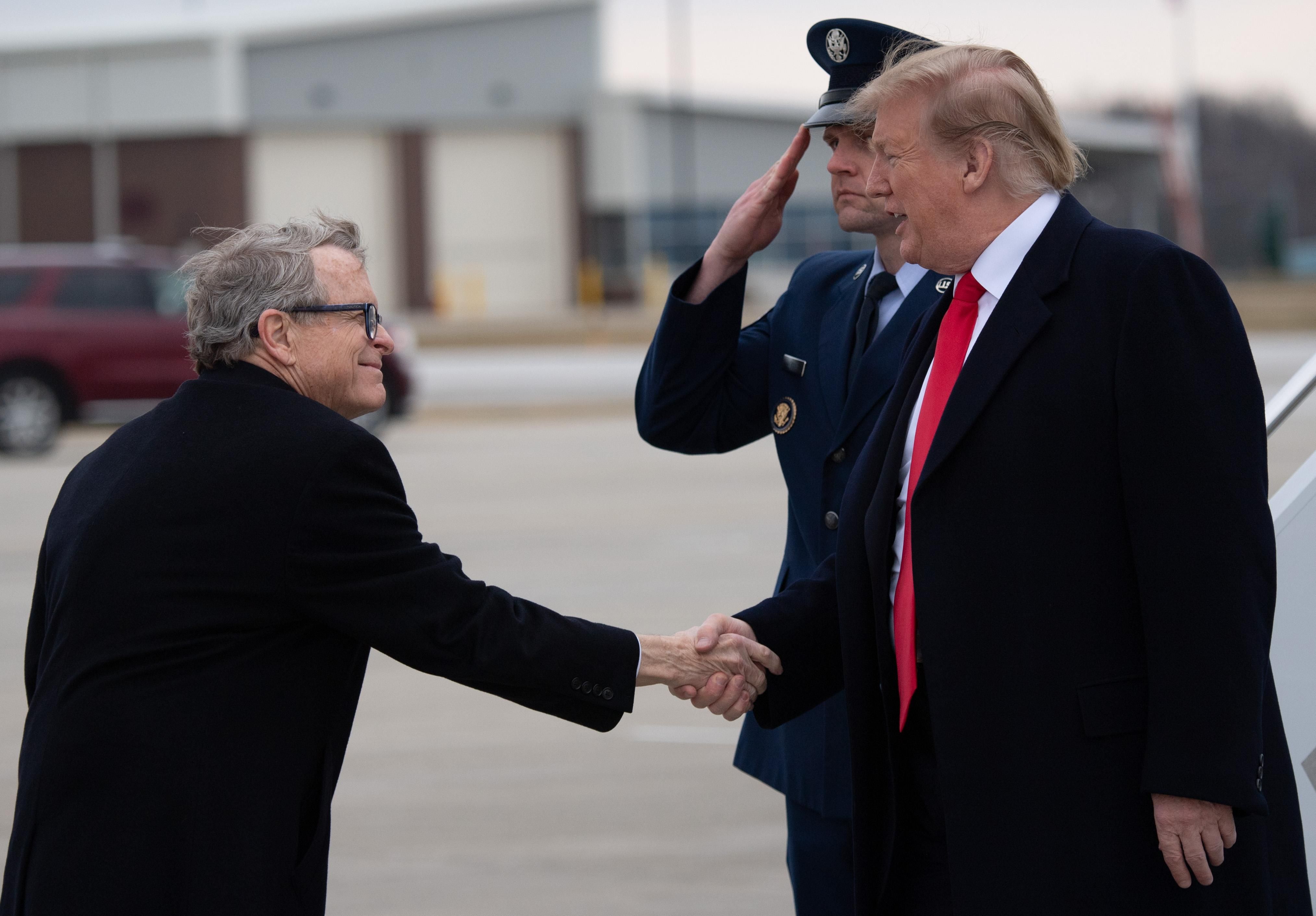 Then-U.S. President Donald Trump shakes hands with Ohio's Republican Gov. Mike DeWine as he disembarks from Air Force One at the Akron-Canton Airport in Canton, Ohio on March 20, 2019.