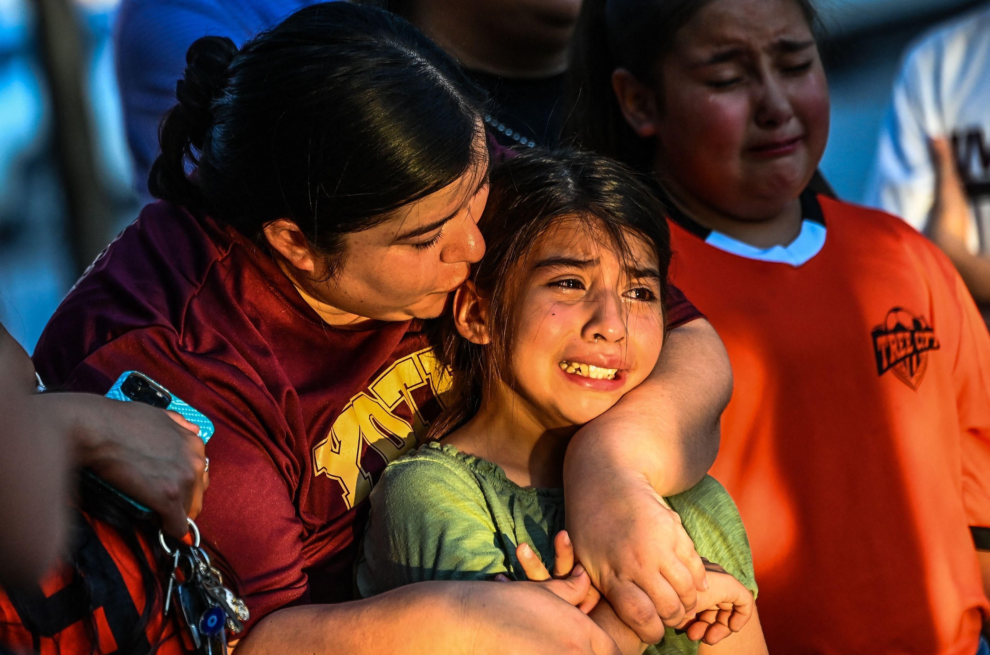Gabriella Uriegas, a soccer teammate of Tess Mata who died in the massacre at an elementary school in Texas, cries while holding her mother Geneva Uriegas as they visit a makeshift memorial outside the Uvalde County Courthouse on May 26, 2022. 