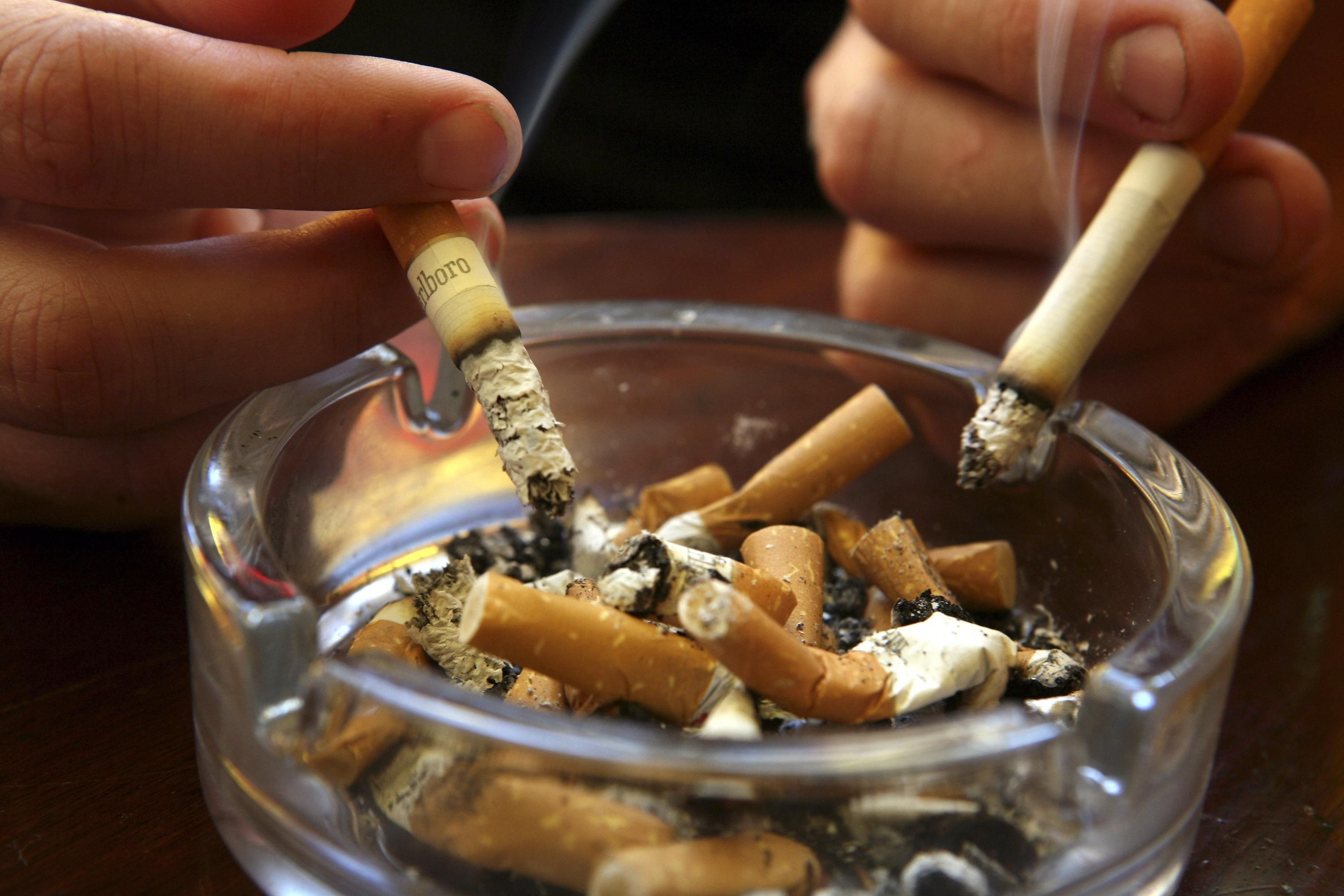 Lit cigarettes are held above a filled ashtray. (Photo: Matt Cardy/Getty Images)
