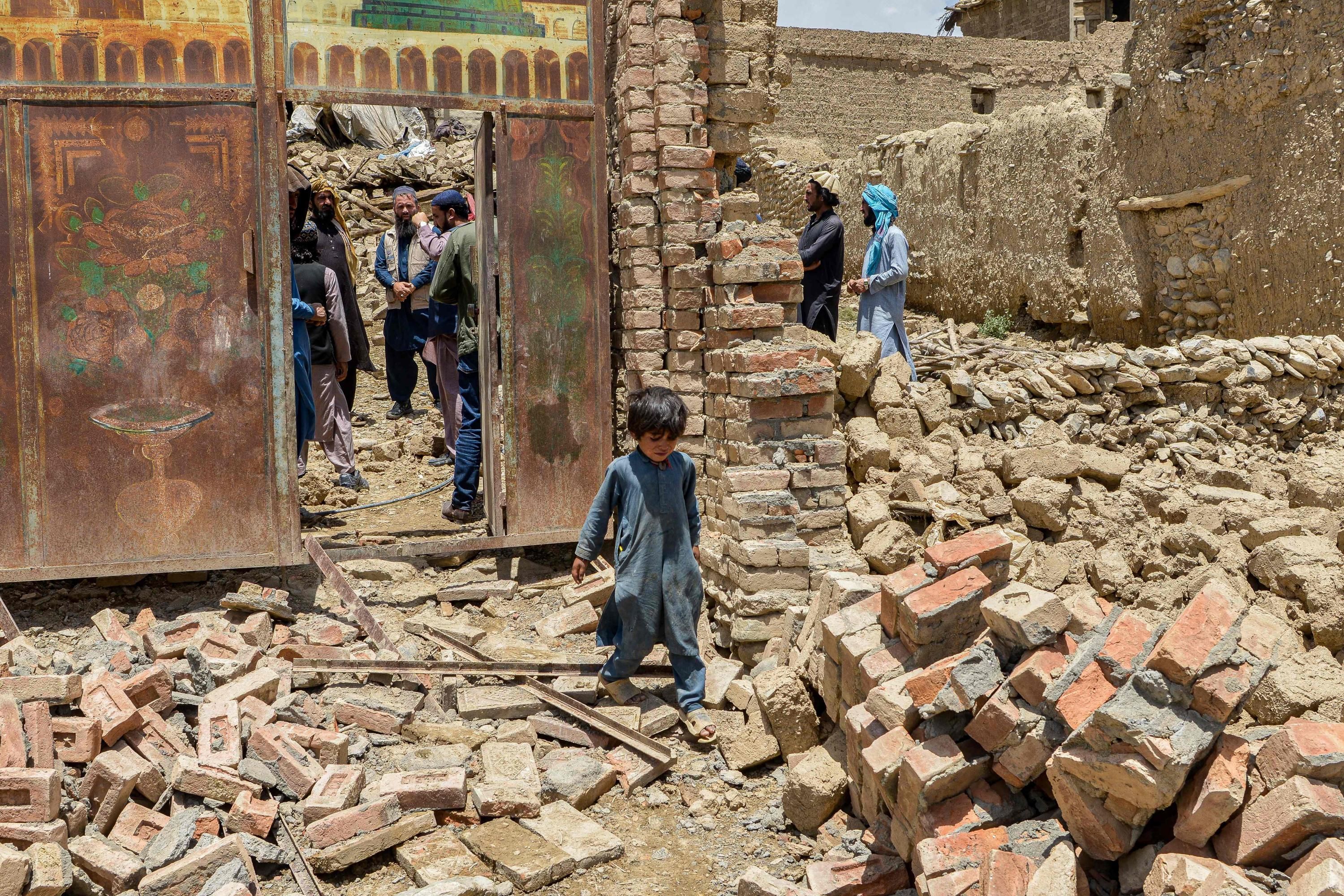 An Afghan child walks amid the rubble of his destroyed home