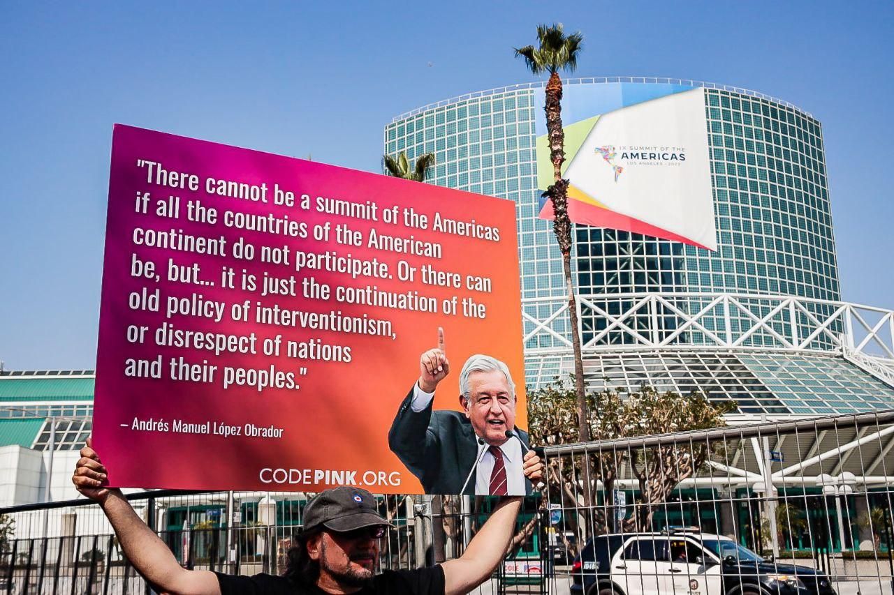 An activist carries a sign featuring Mexican President Andrés Manuel López Obrador's critique of U.S. President Joe Biden's decision to exclude Cuba, Nicaragua, and Venezuela from the Summit of the Americas in downtown Los Angeles on June 9, 2022. 