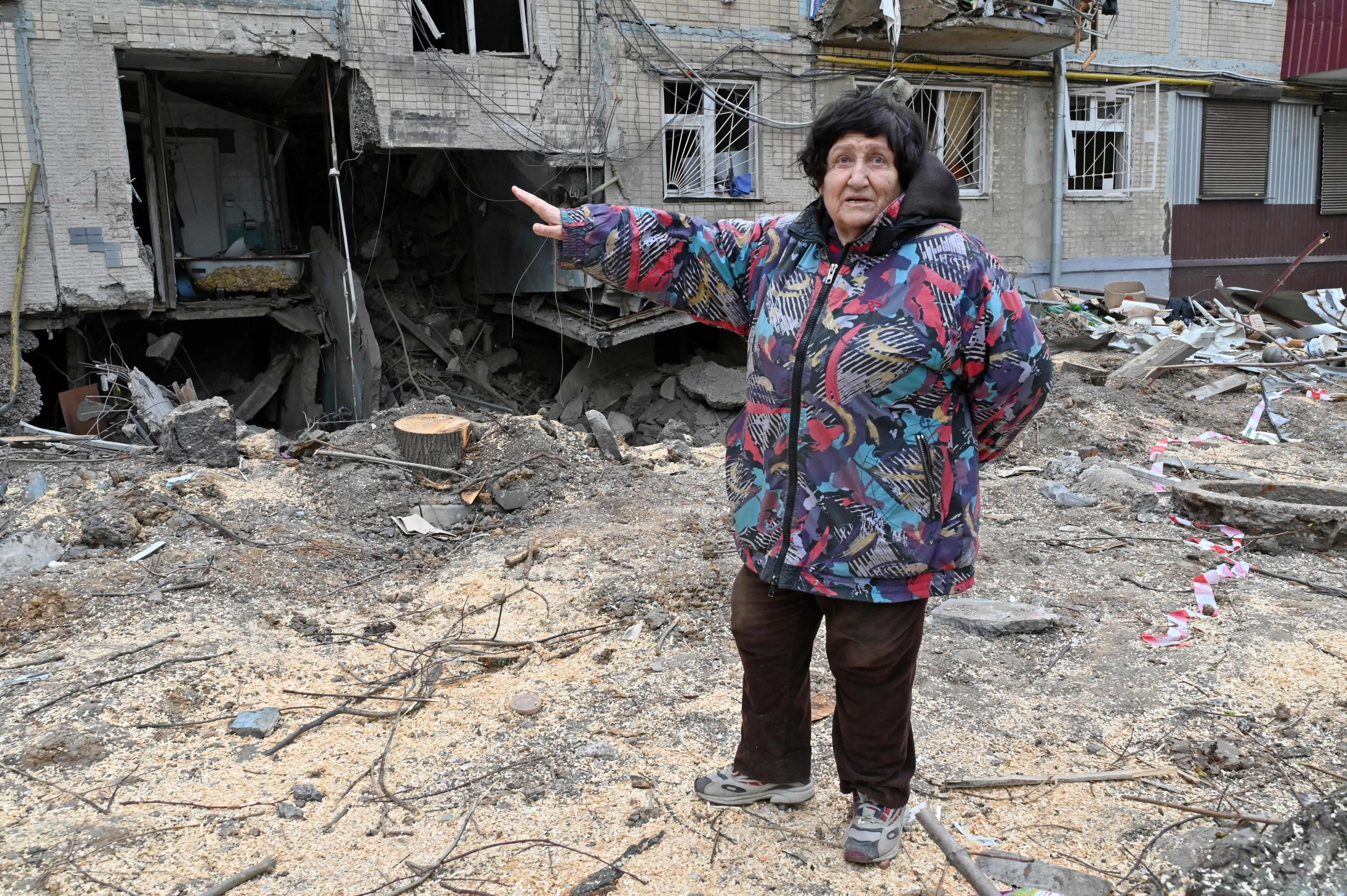 A woman gestures toward damage done by bombing in Kharkiv