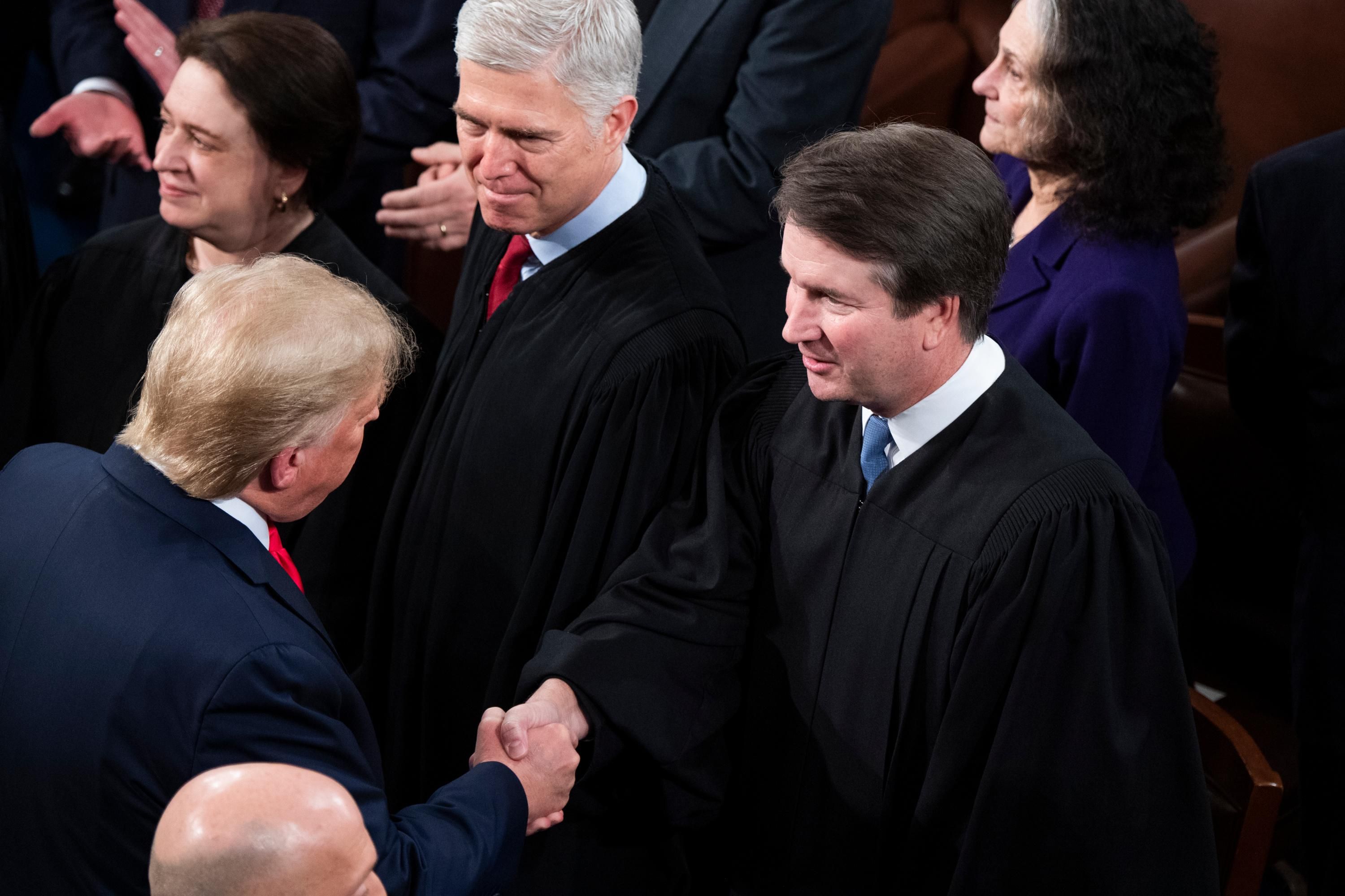Then-President Donald Trump greets Justices Brett Kavanaugh and Neil Gorsuch