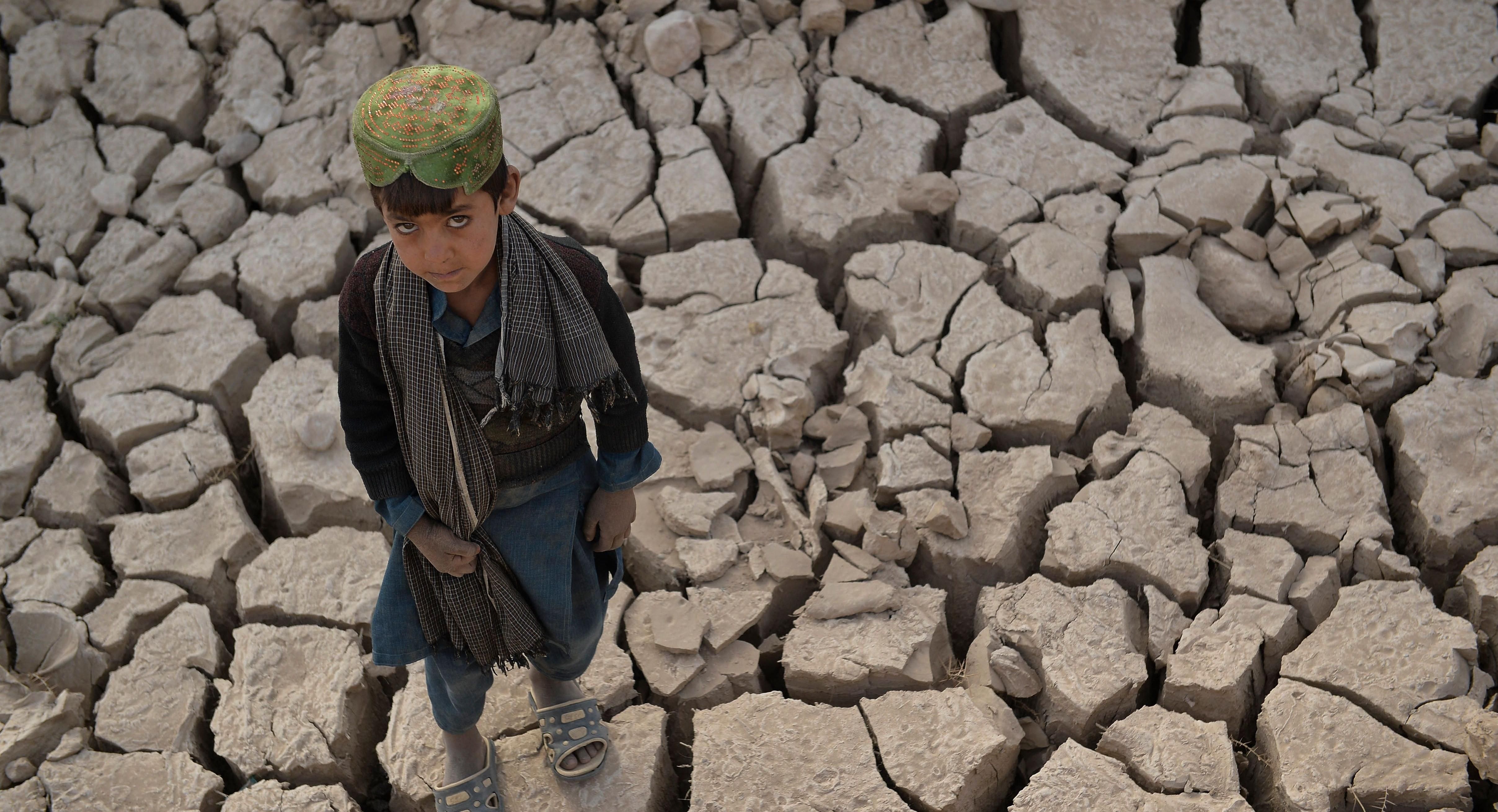 Afghan boy standing in drought-stricken flats