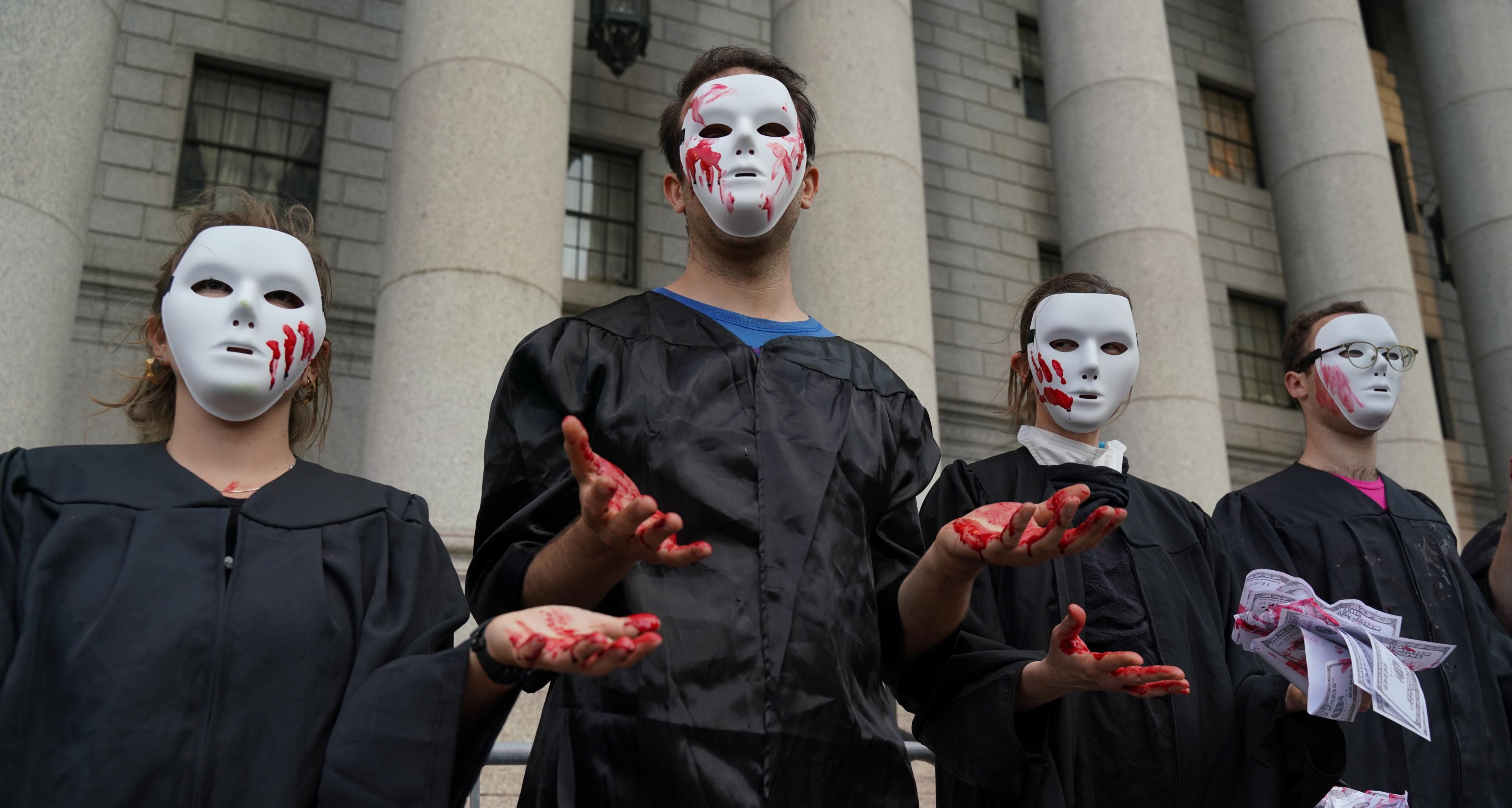 Demonstrators dressed as Supreme Court Justices with blood-soaked hands