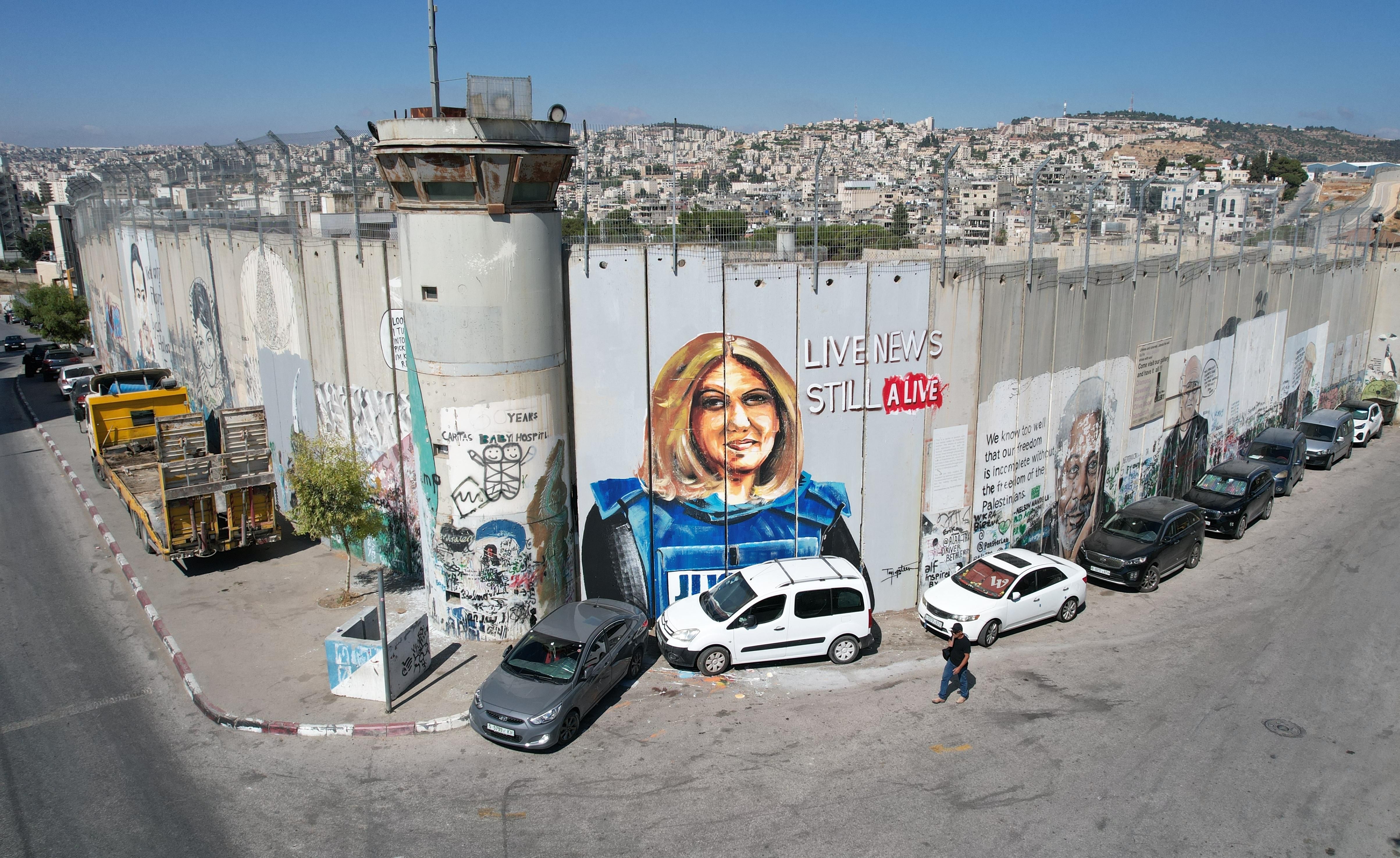 Palestinian artist Takiyuddin Sebatin preparing a graffiti on the separation wall in the West Bank for US President Joe Biden, who is planning to visit Bethlehem in the middle of this month, depicting the photograph of Al Jazeera journalist Shireen Abu Akleh, killed by Israeli forces, on July 06, 2022 in Bethlehem, West Bank. 