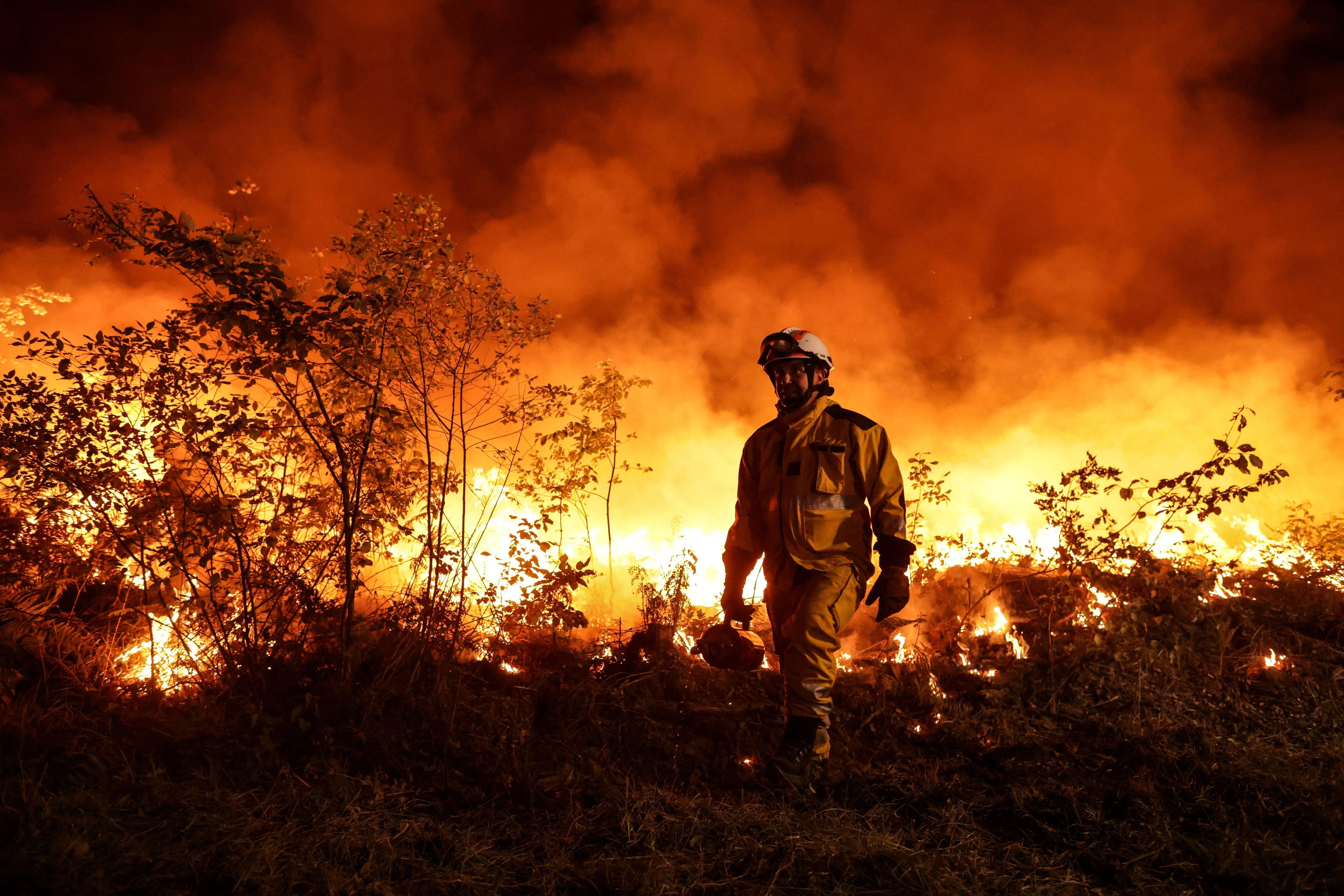 Tactical firefighters work to prevent a wildfire from spreading further as the winds change in Louchats, France on July 17, 2022.