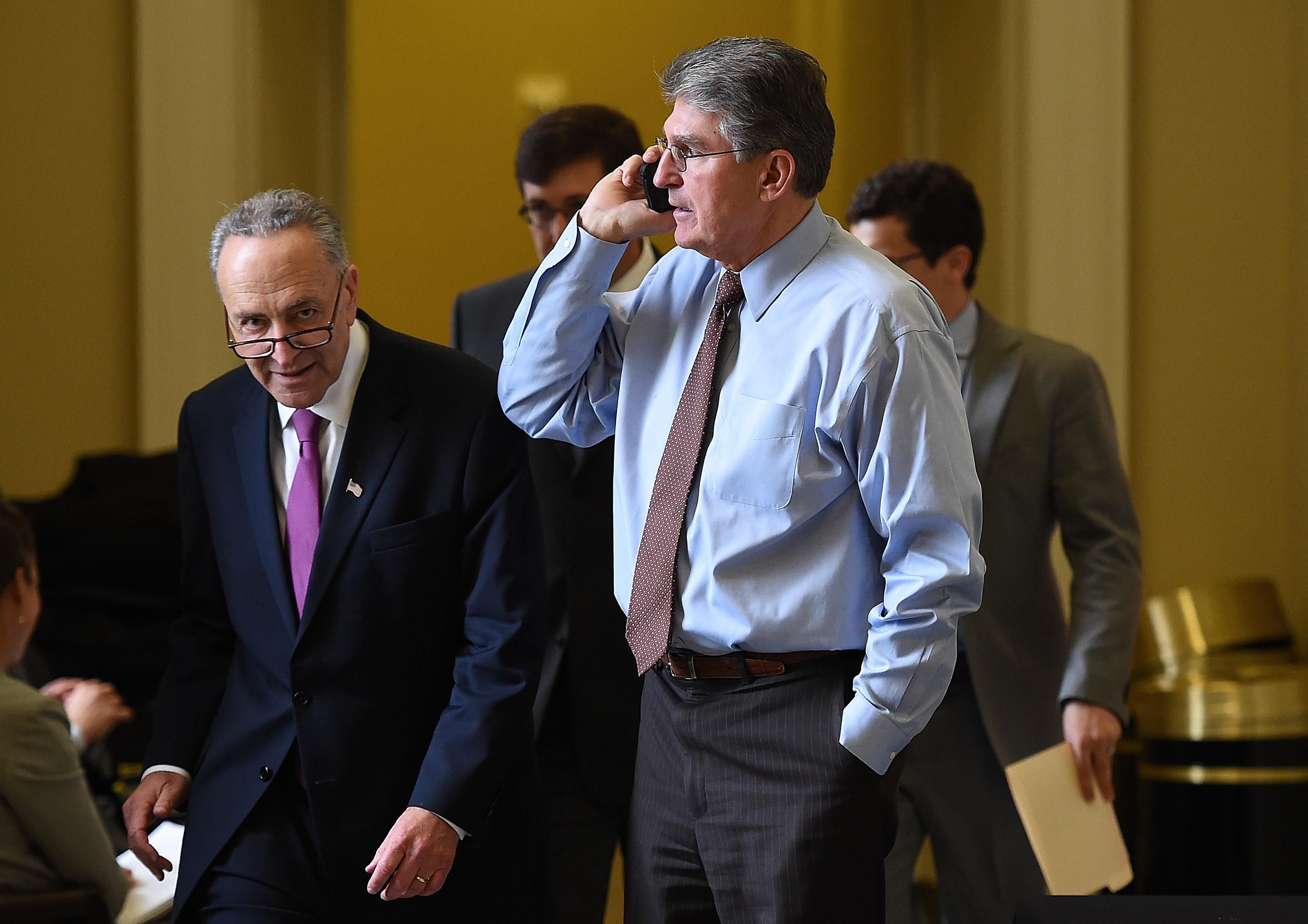 Schumer passes Manchin as he speaks on the phone
