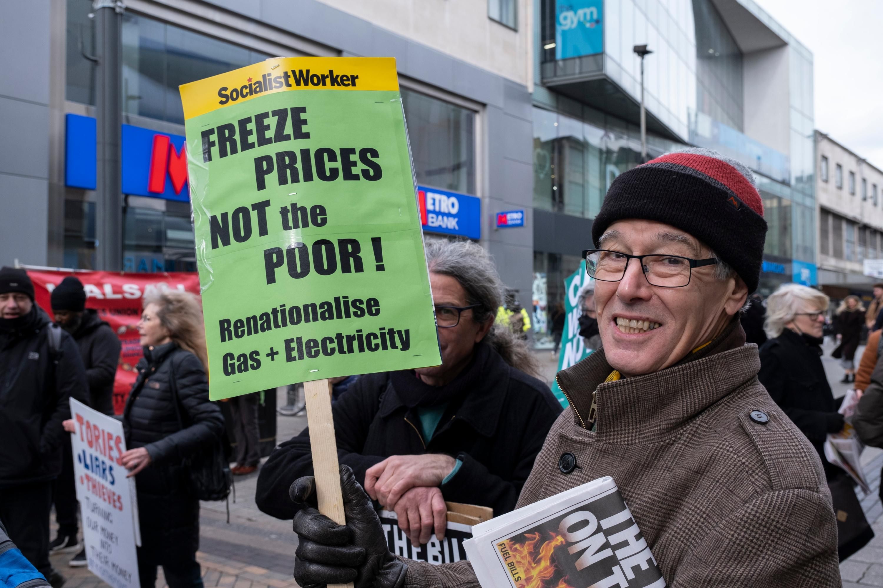 protester holds sign that says freeze prices not the poor