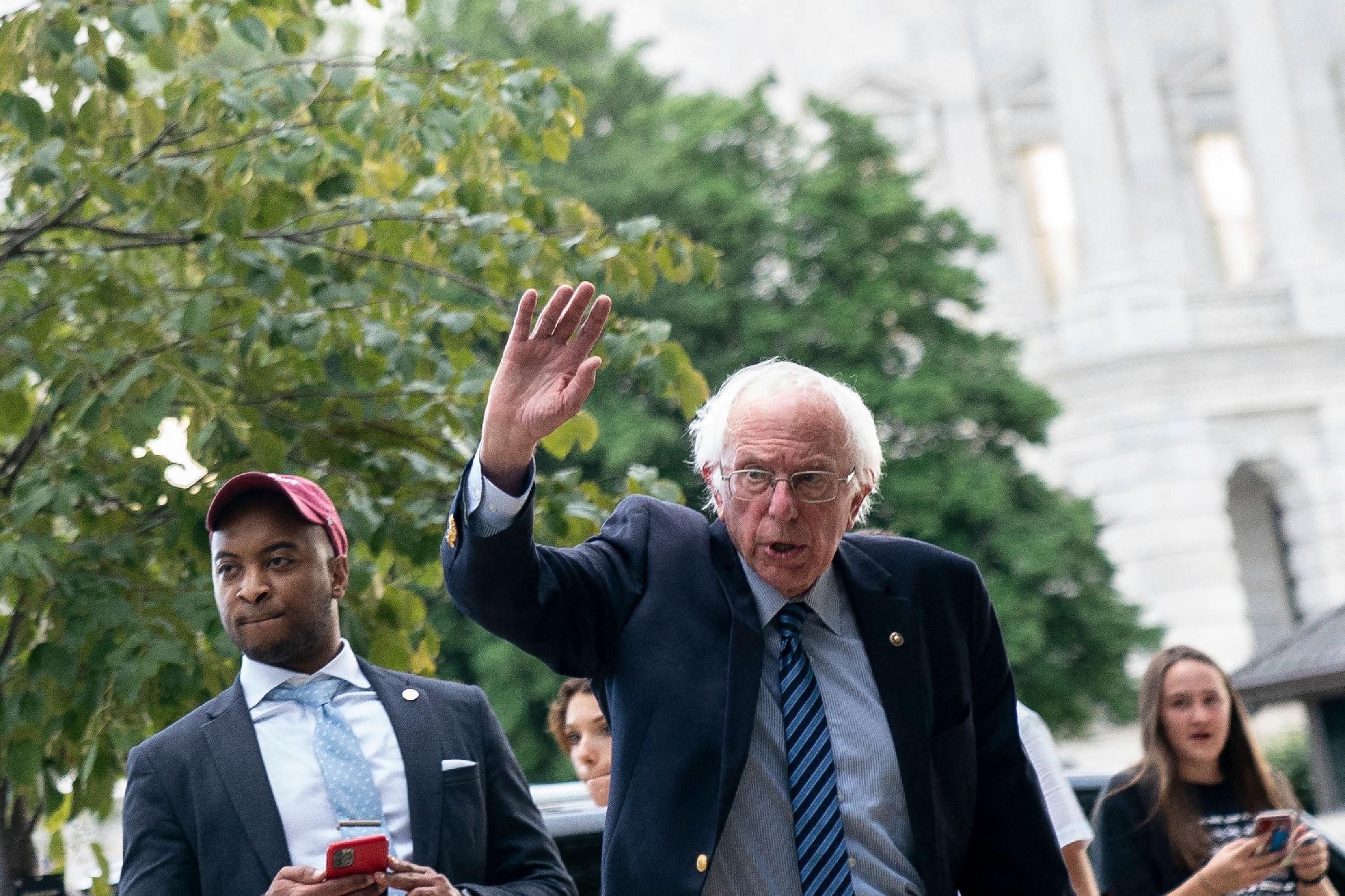 Sen. Bernie Sanders waves at demonstrators on Capitol Hill