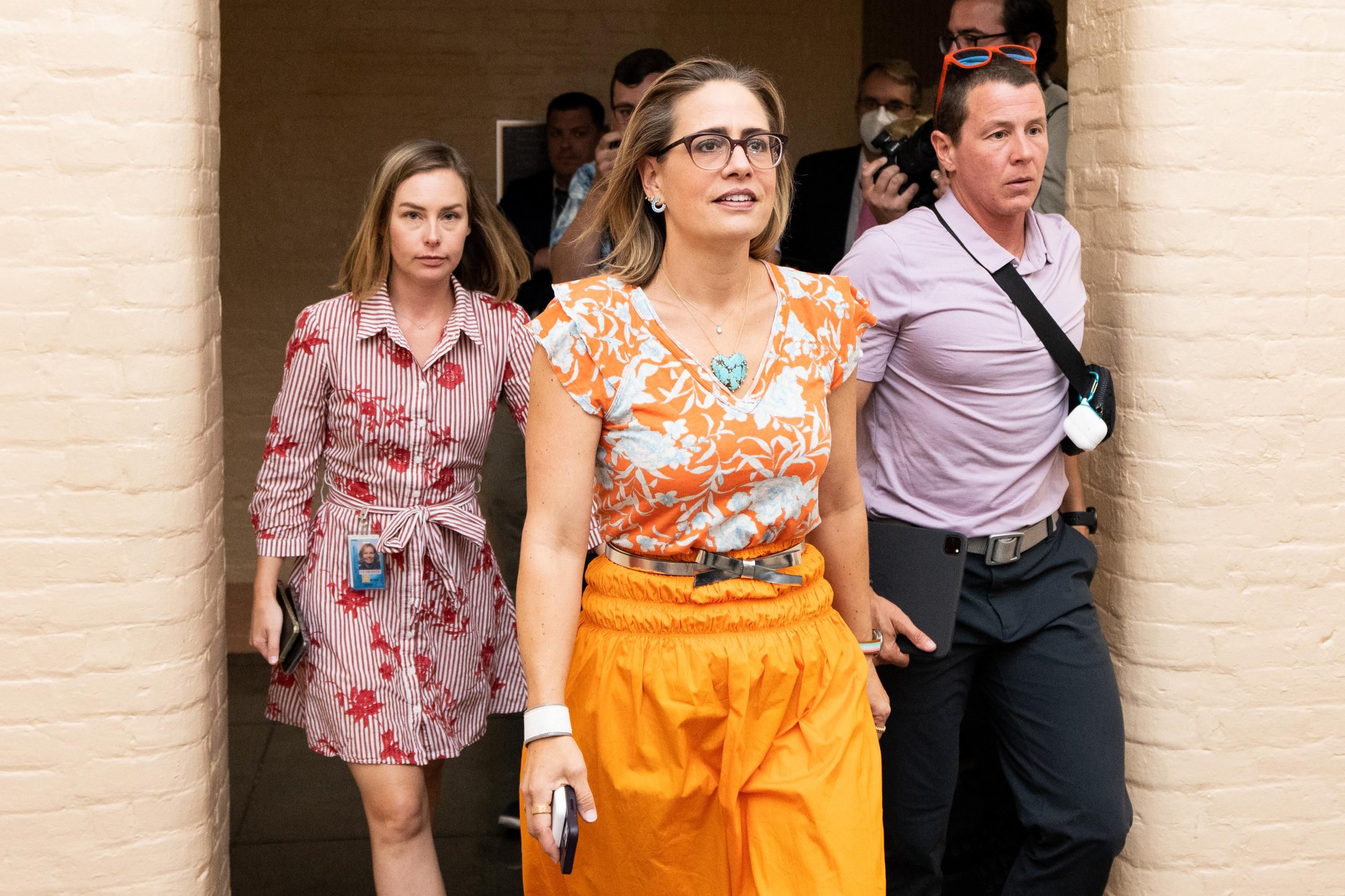 Sen. Kyrsten Sinema walks with staff near the U.S. Capitol