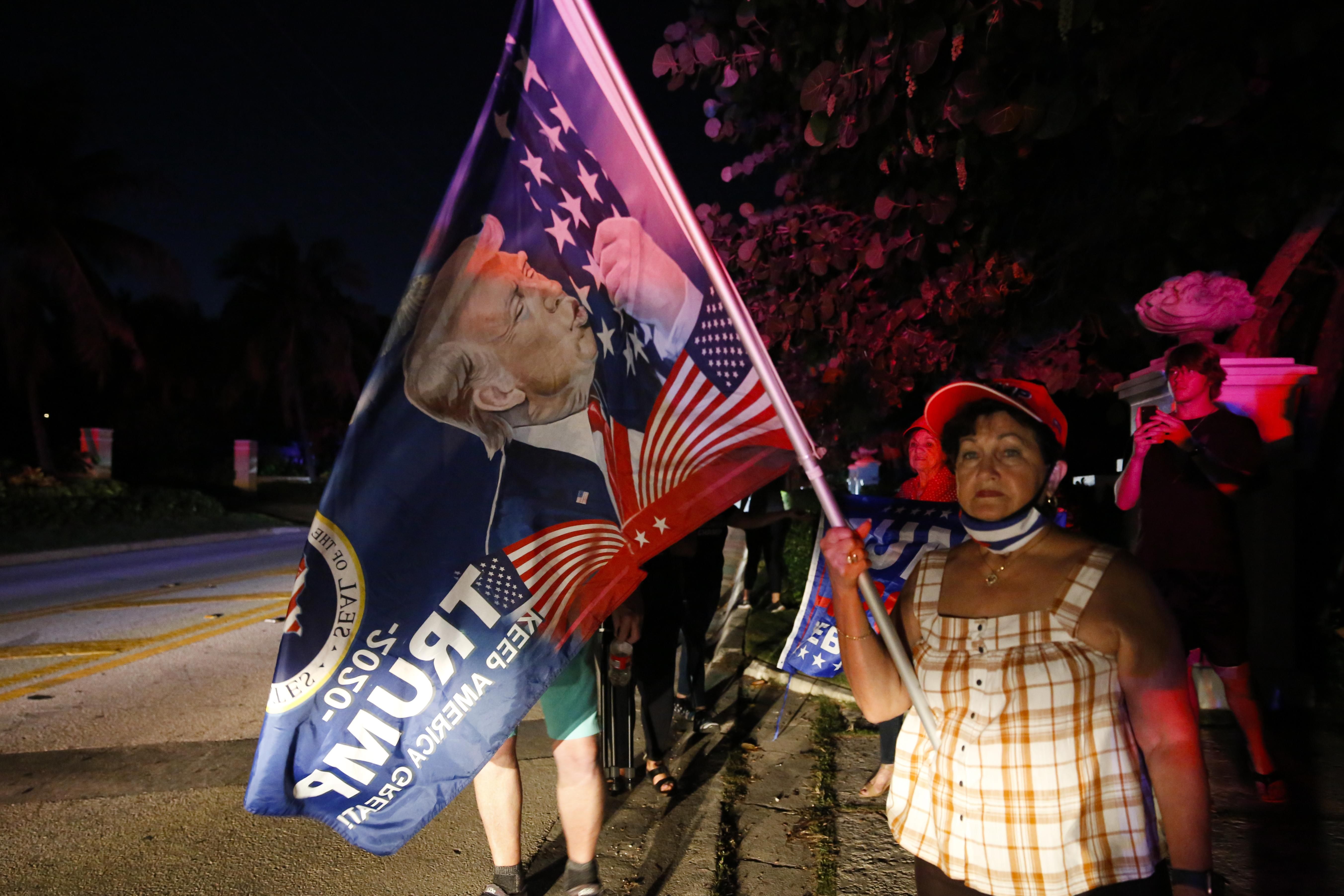 Supporters of former President Donald Trump hold flags in front of his home at Mar-a-Lago on August 8, 2022 in Palm Beach, Florida.