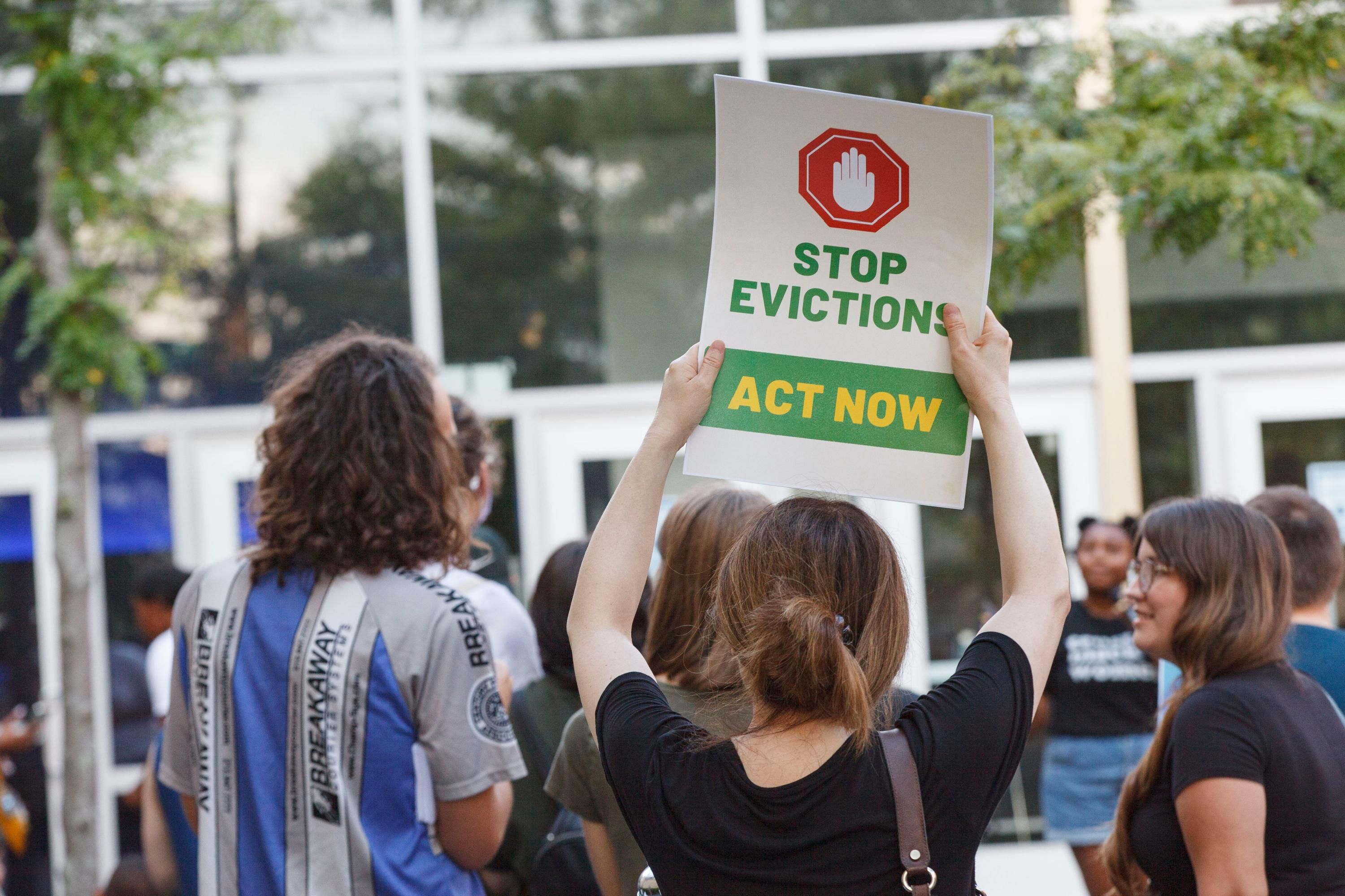 Sign reading, "Stop evictions, act now" at a protest