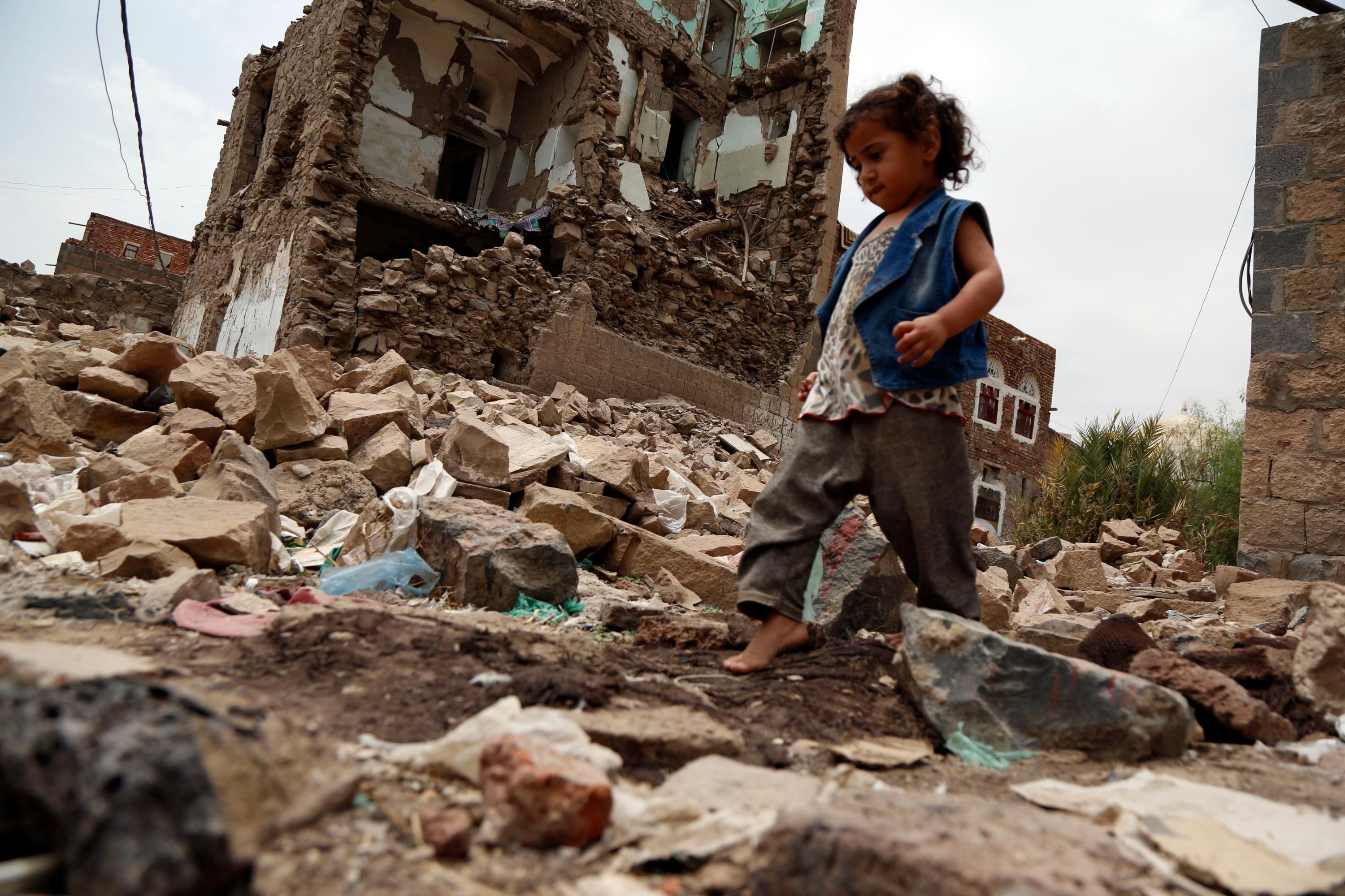 Yemeni child walking through rubble