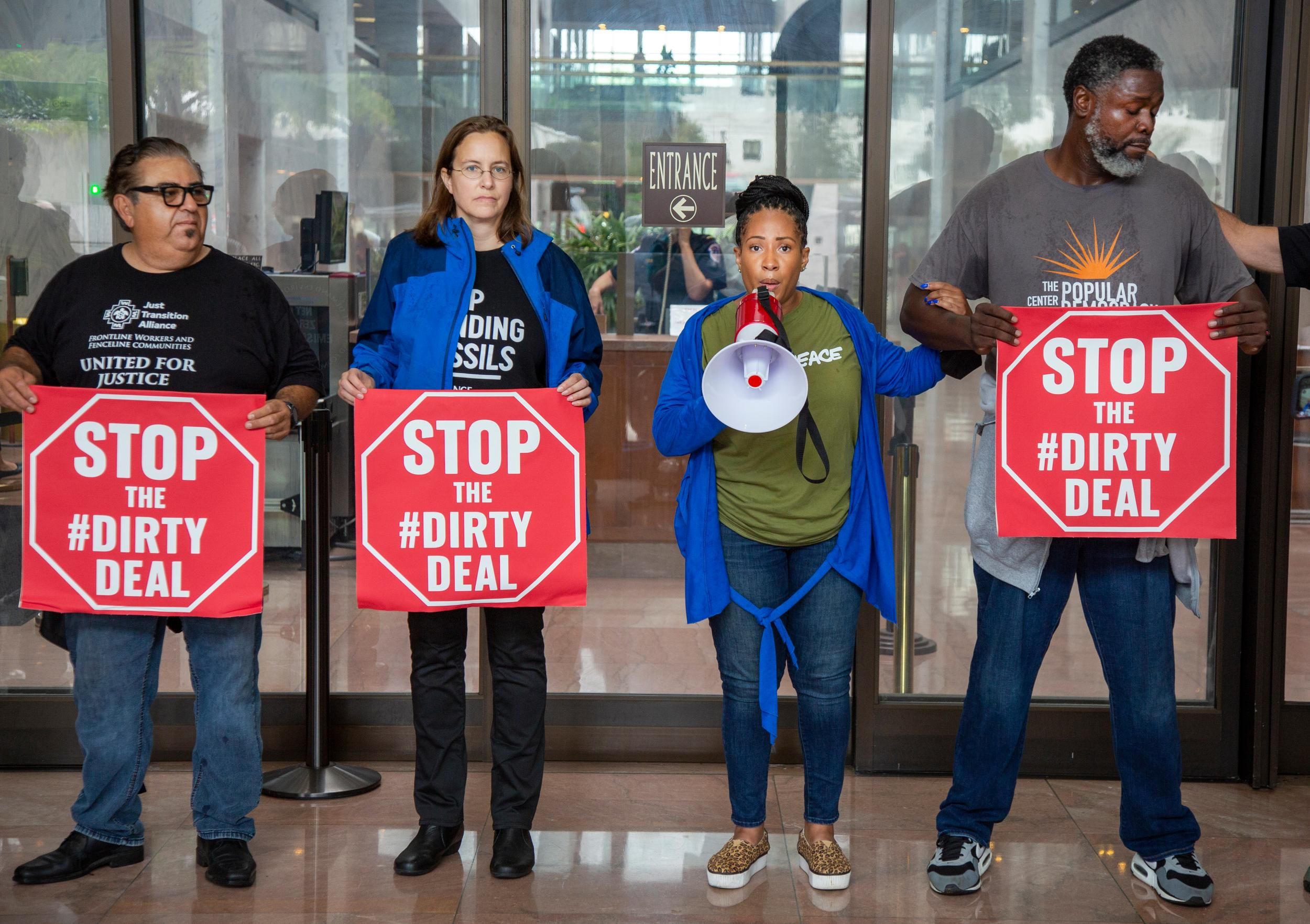 Climate leaders risking arrest hold signs saying "Stop the #DirtyDeal"