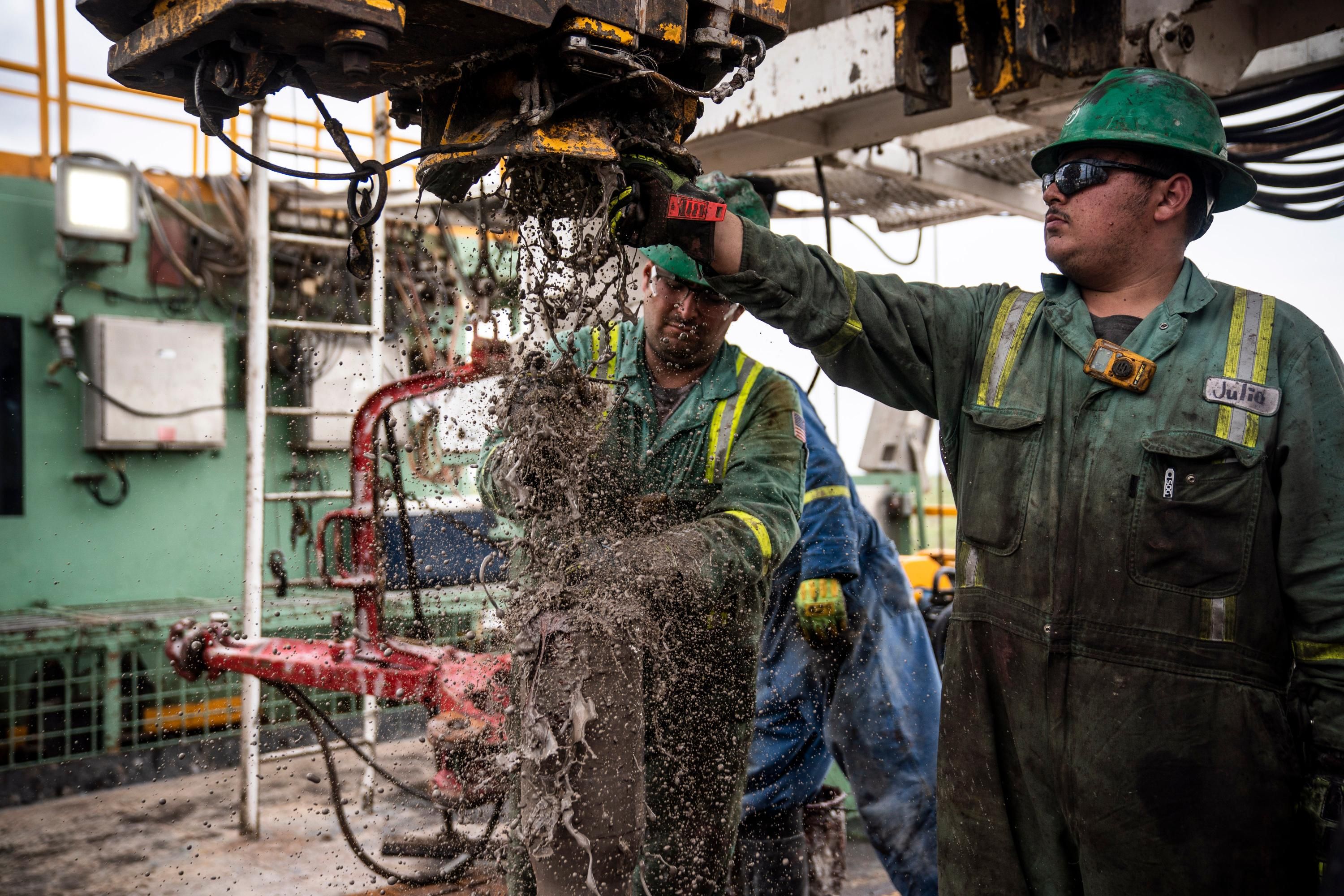 Workers extract oil from a well in the Permian Basin
