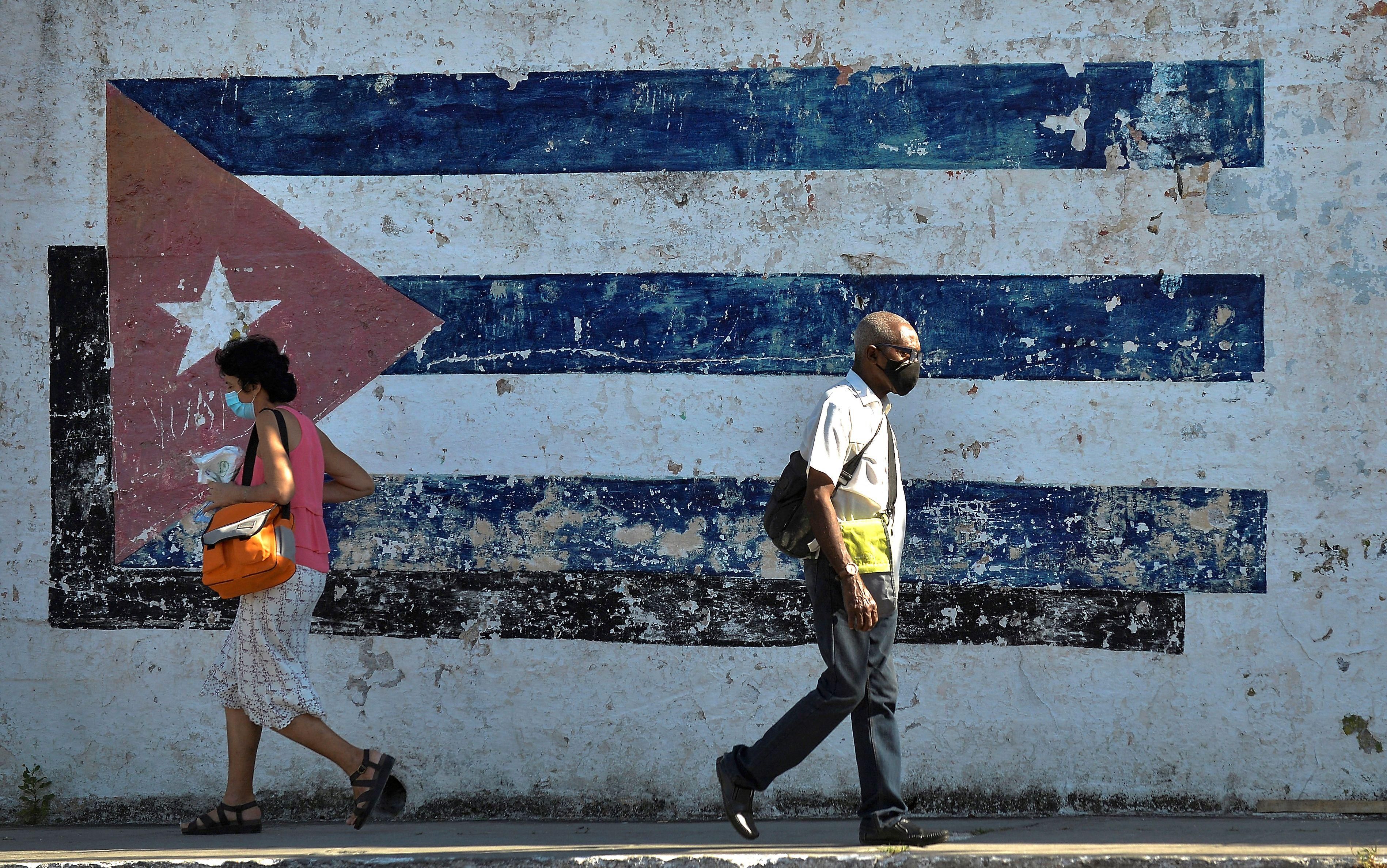 People walk near a mural depicting a Cuban flag in Havana on April 16, 2021. 