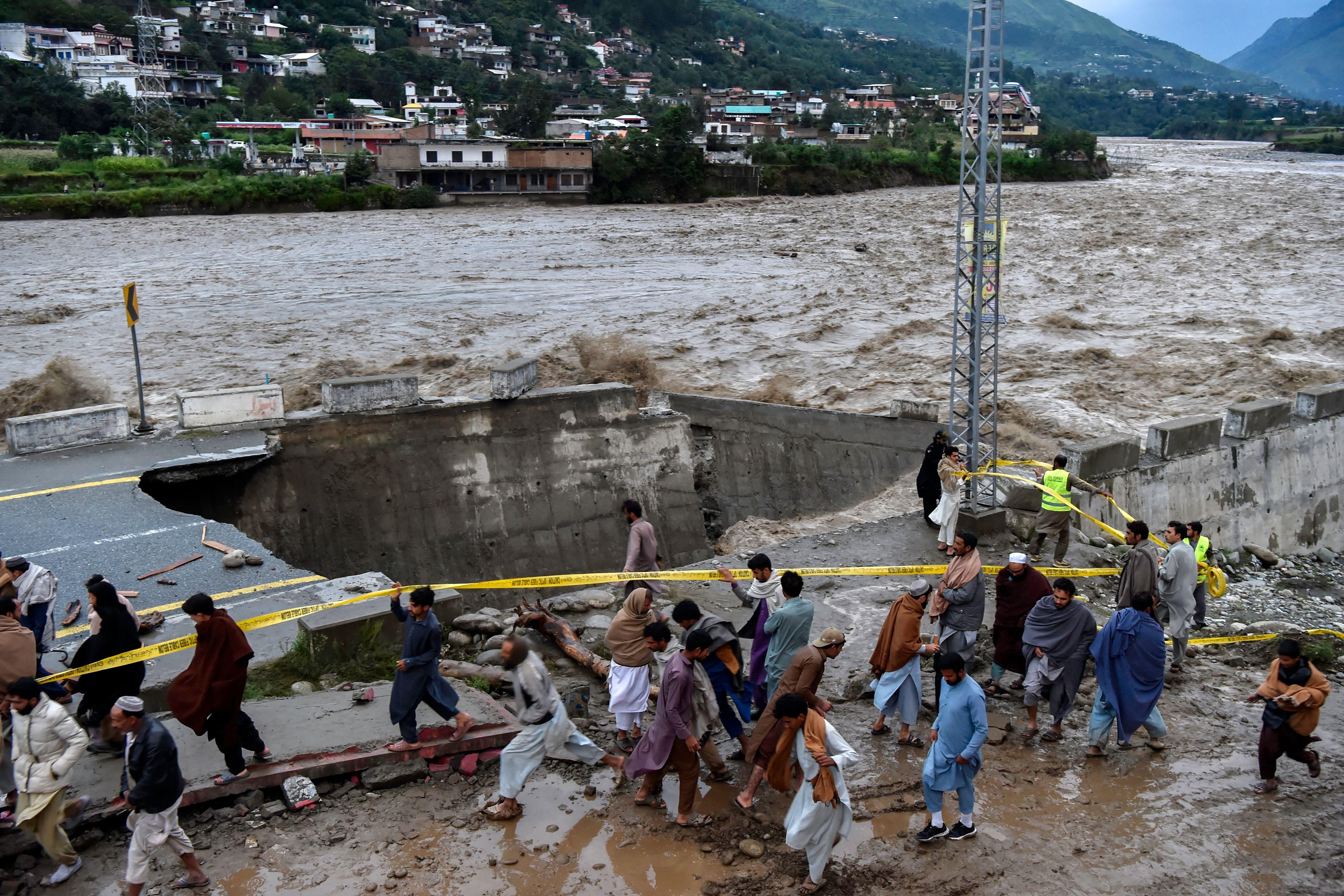 People gather in front of a road damaged by heavy monsoon rains in Madyan, Pakistan on August 27, 2022.