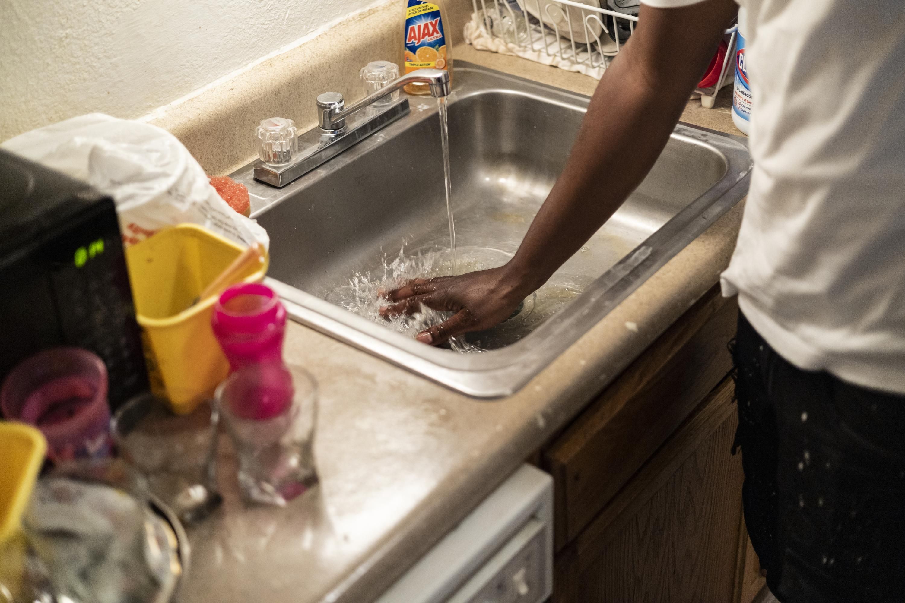 Terrence Carter mixes bleach and soap with water before washing dishes on September 1, 2022 in Jackson, Mississippi.