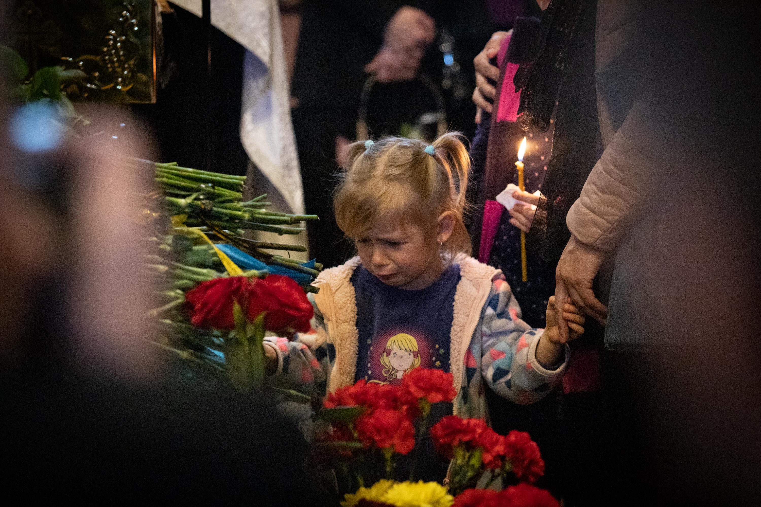 Child mourns at funeral during Ukraine war