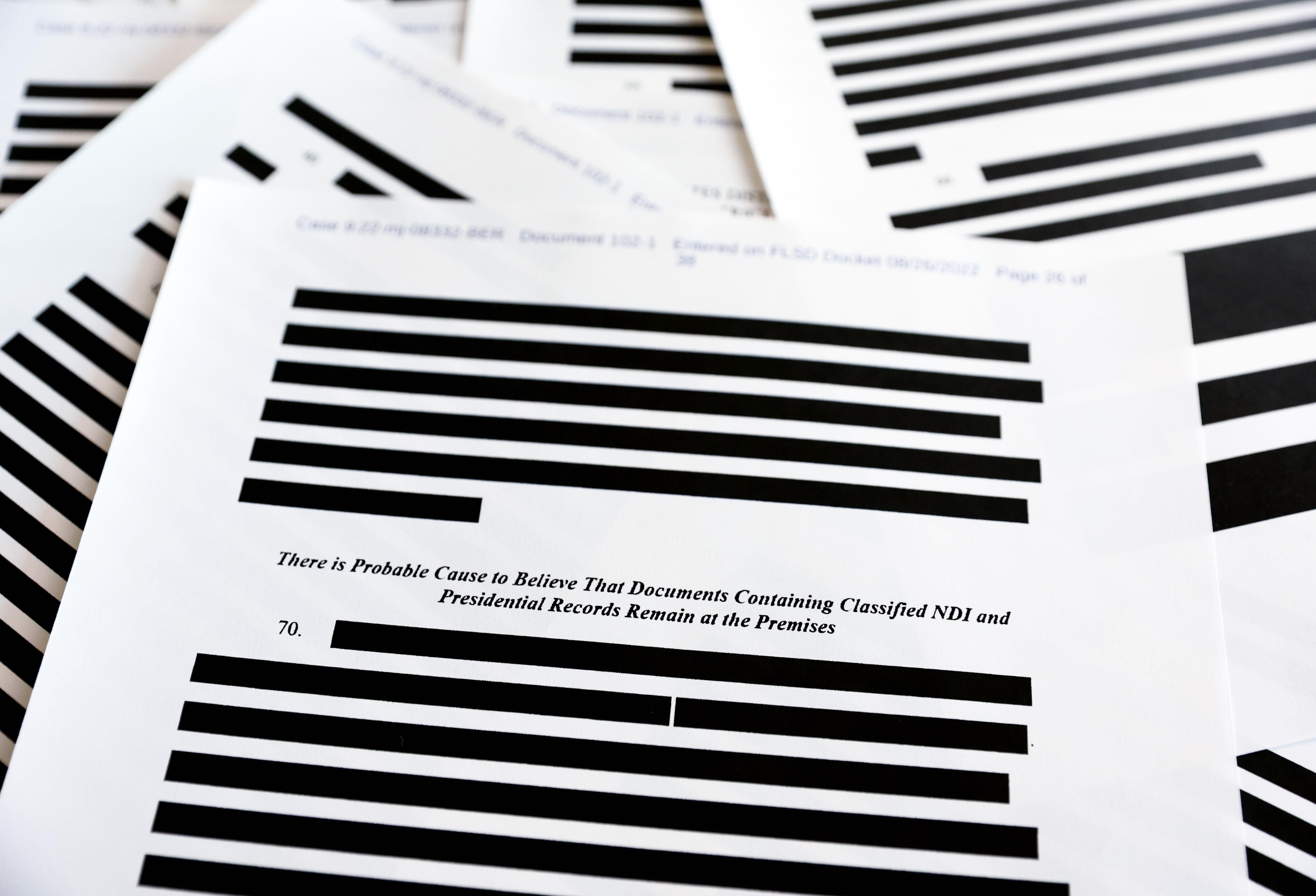 Heavily redacted classified documents are pictured
