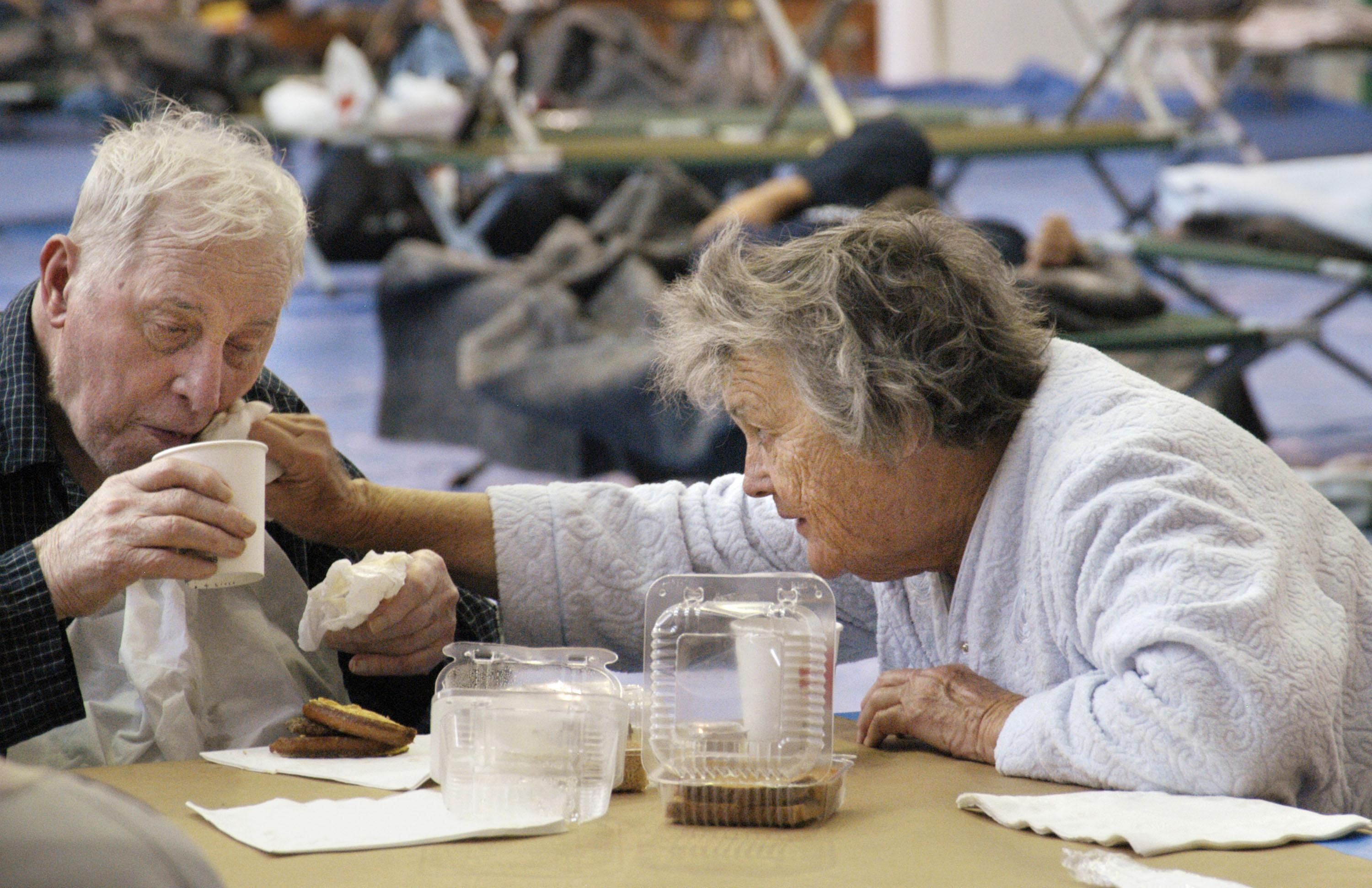 Wife helping her elderly husband at an emergency shetler