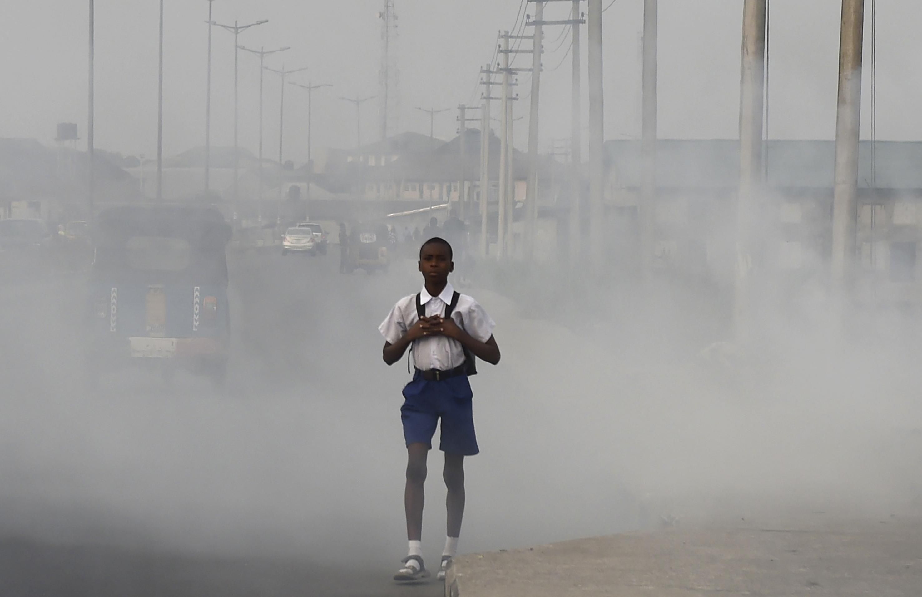 Boy walks through smog in Port Harcourt, Nigeria
