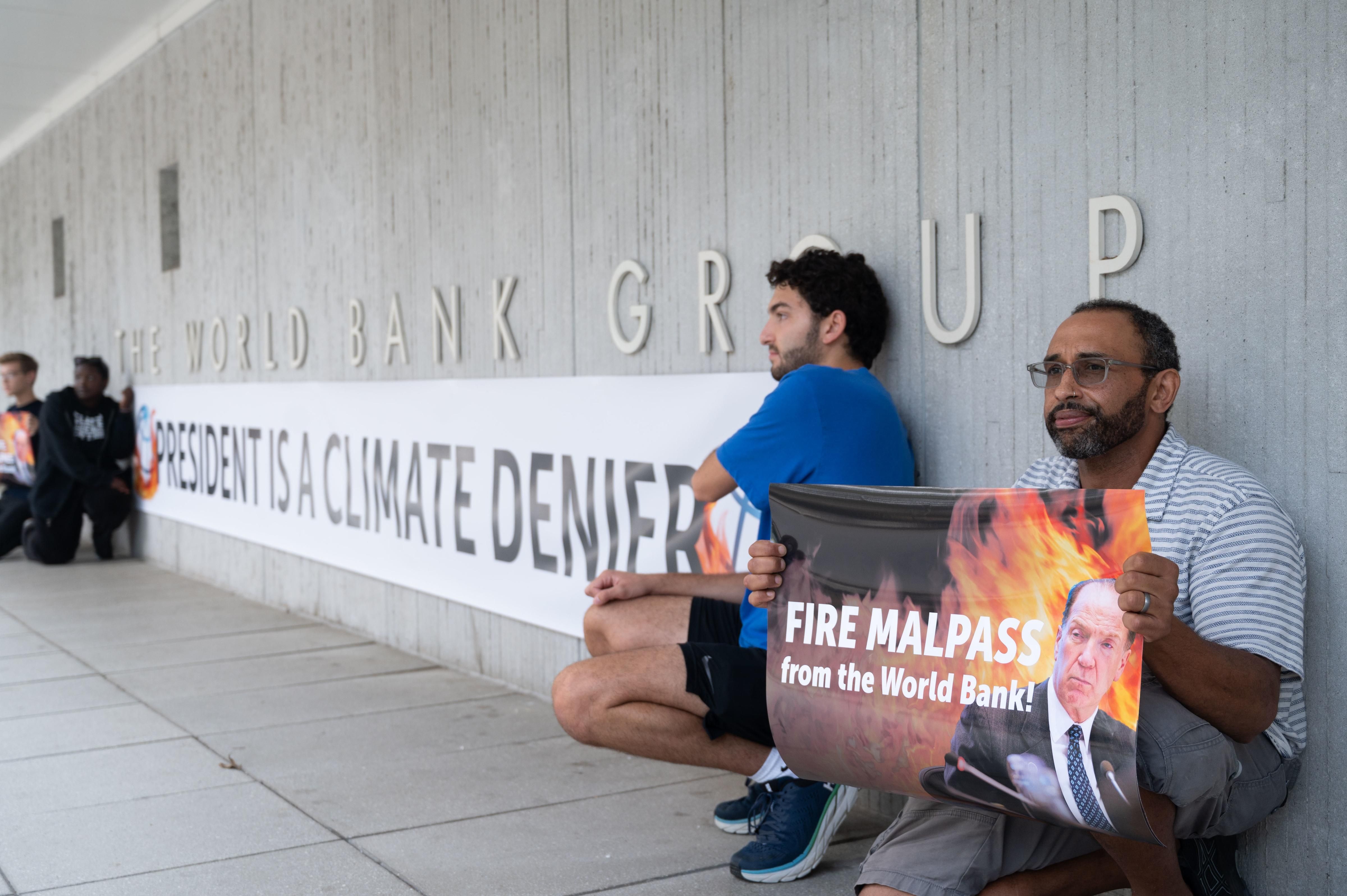 Activists display a banner describing World Bank President David Malpass as a climate denier in front of the bank's headquarters in Washington, D.C. on September 22, 2022.