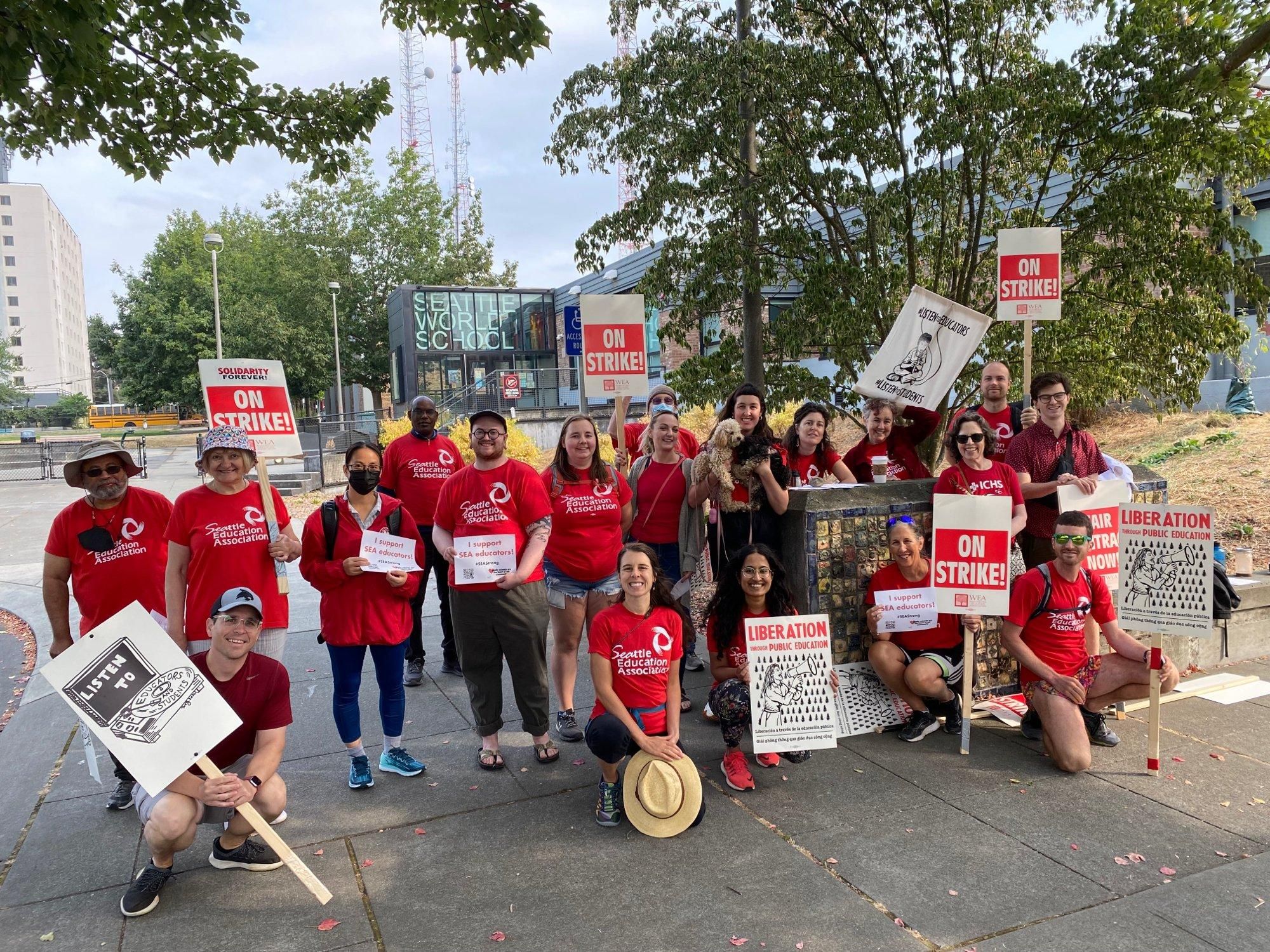 Members of the Seattle Education Association pose in front of one of the city's public school buildings while on strike on September 12, 2022.