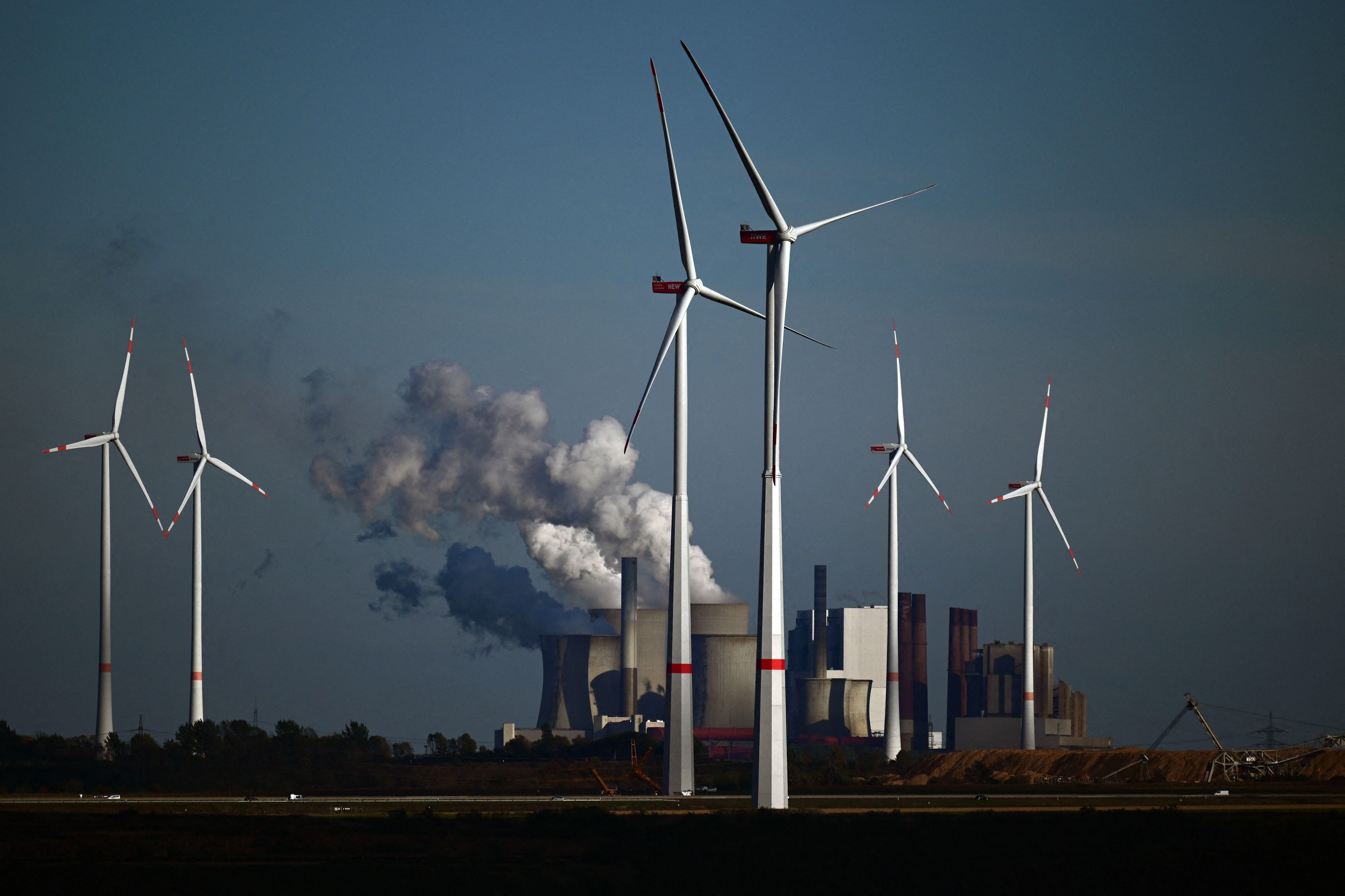 Wind turbines are shown in front of a coal-fired power plant operated by energy giant RWE near Niederaussem, Germany on October 5, 2022.