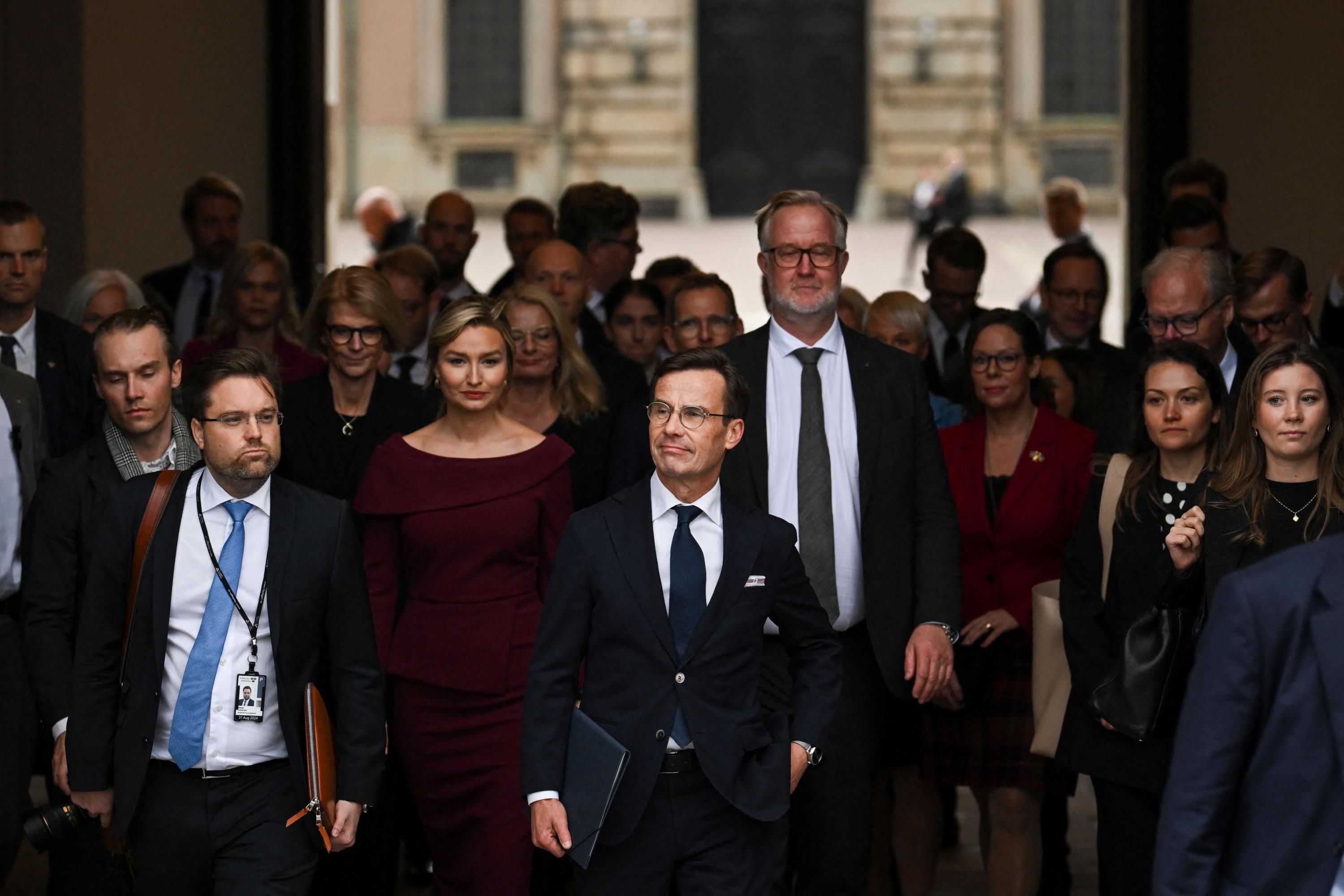 Sweden's right-wing prime minister walks with members of the new government