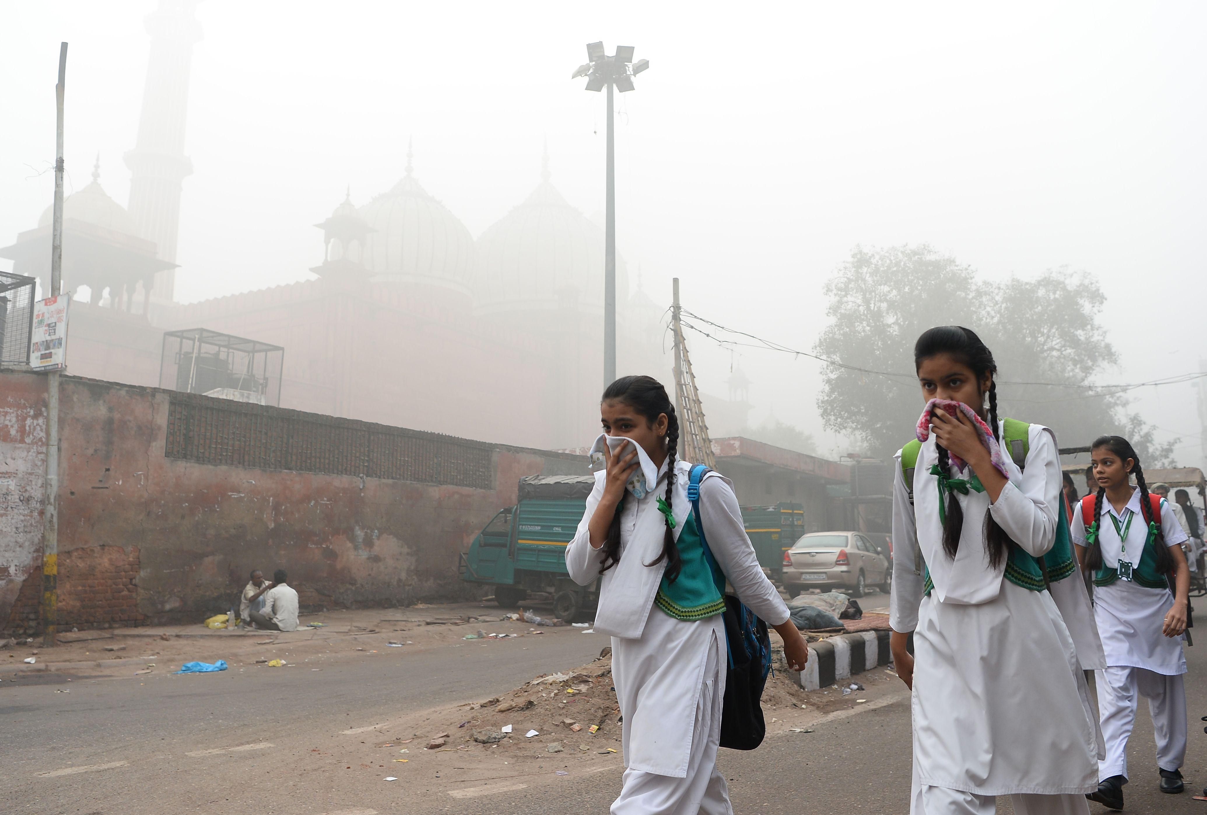 Indian students cover their faces as they walk to school amid heavy smog in New Delhi on November 8, 2017