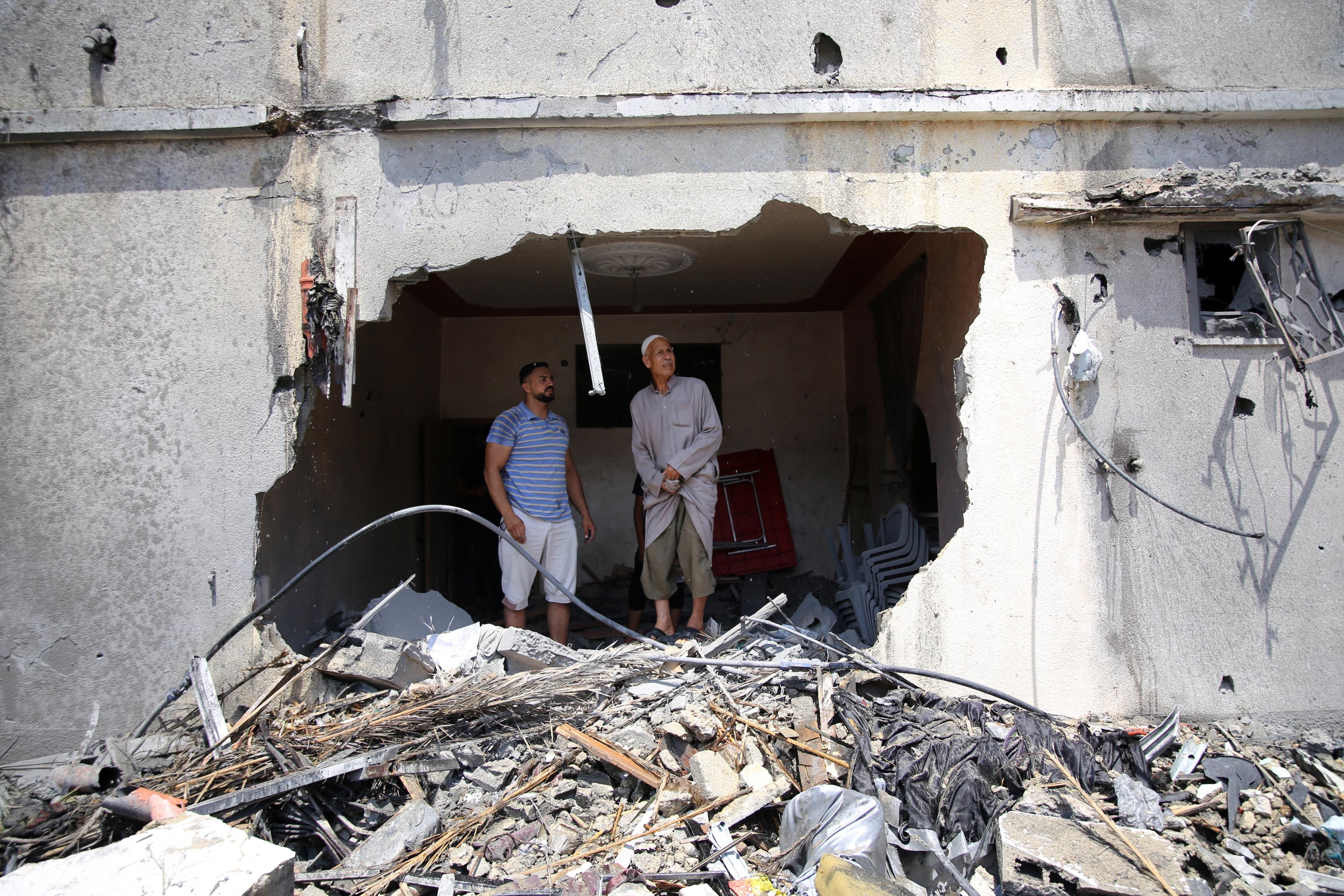 Palestinians stand in ruins of building