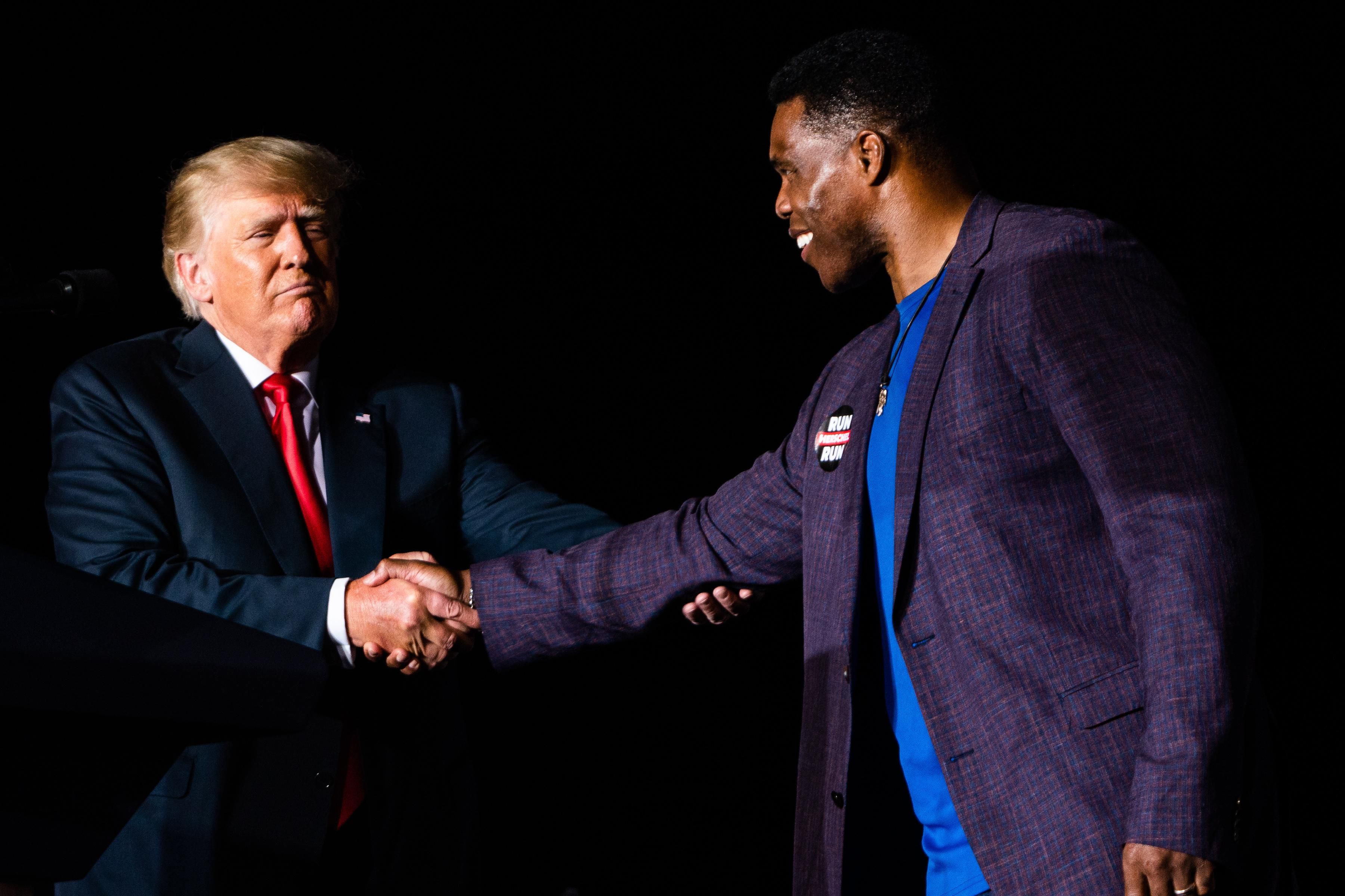 Former U.S. President Donald Trump shakes hands with Republican Senate candidate Herschel Walker at a rally in Perry, Georgia on September 25, 2021.